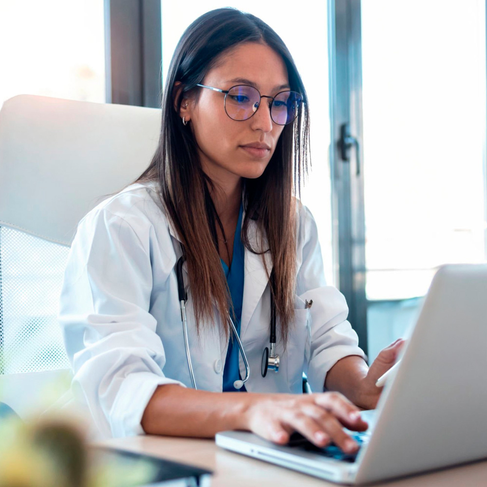 Female doctor working on laptop during telehealth session.