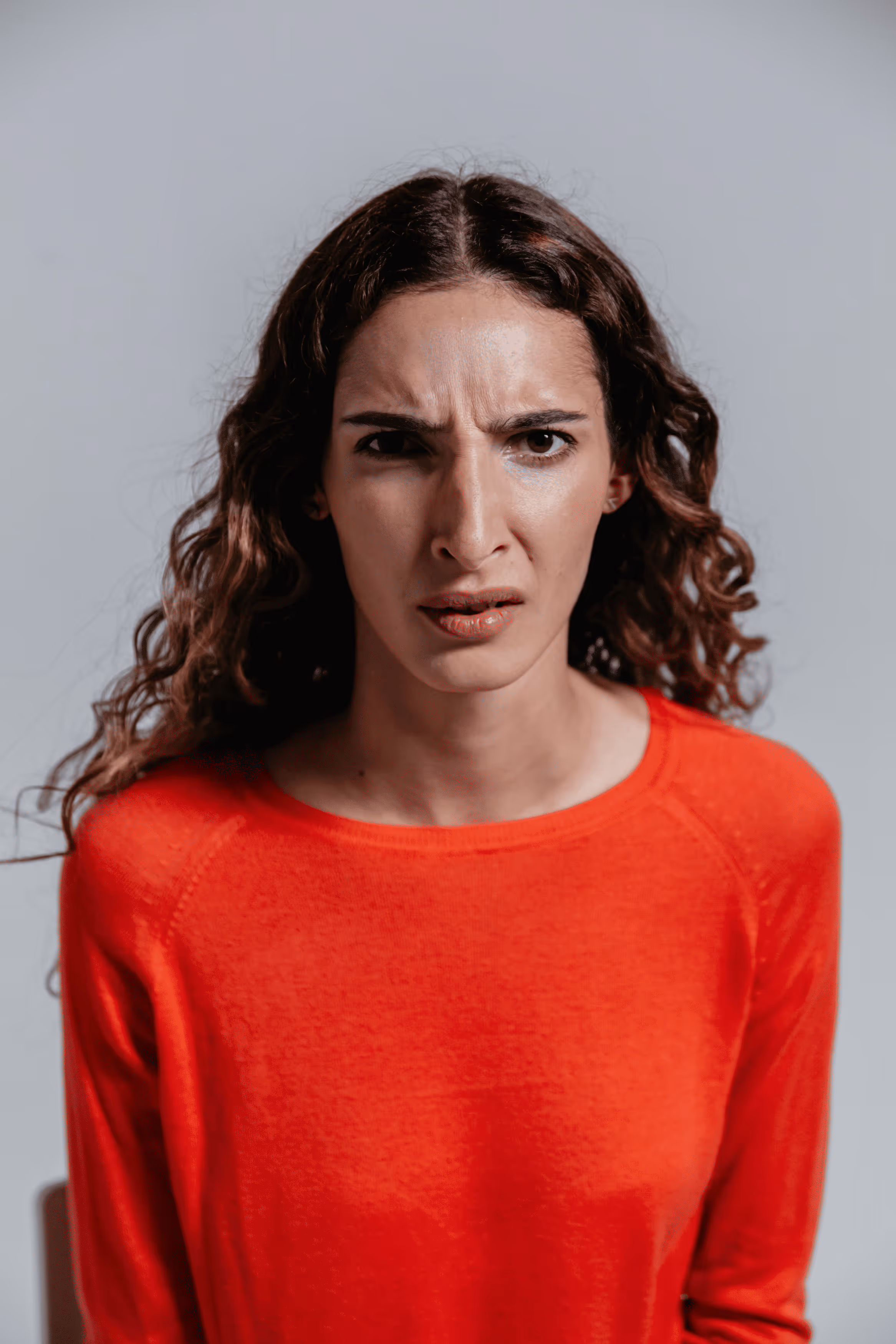 Woman sitting on couch holding her stomach in discomfort.