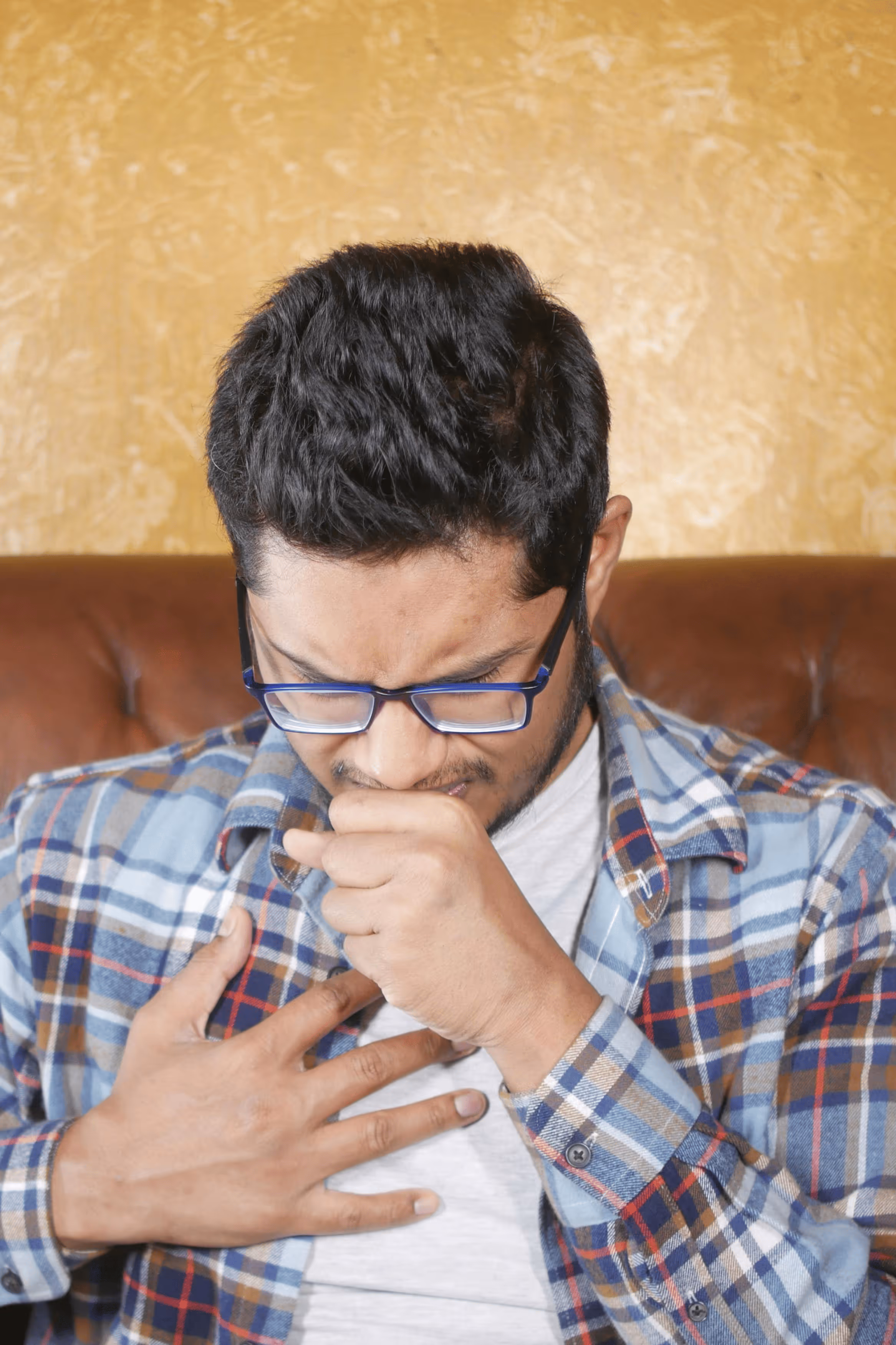 Woman sitting on couch holding her stomach in discomfort.
