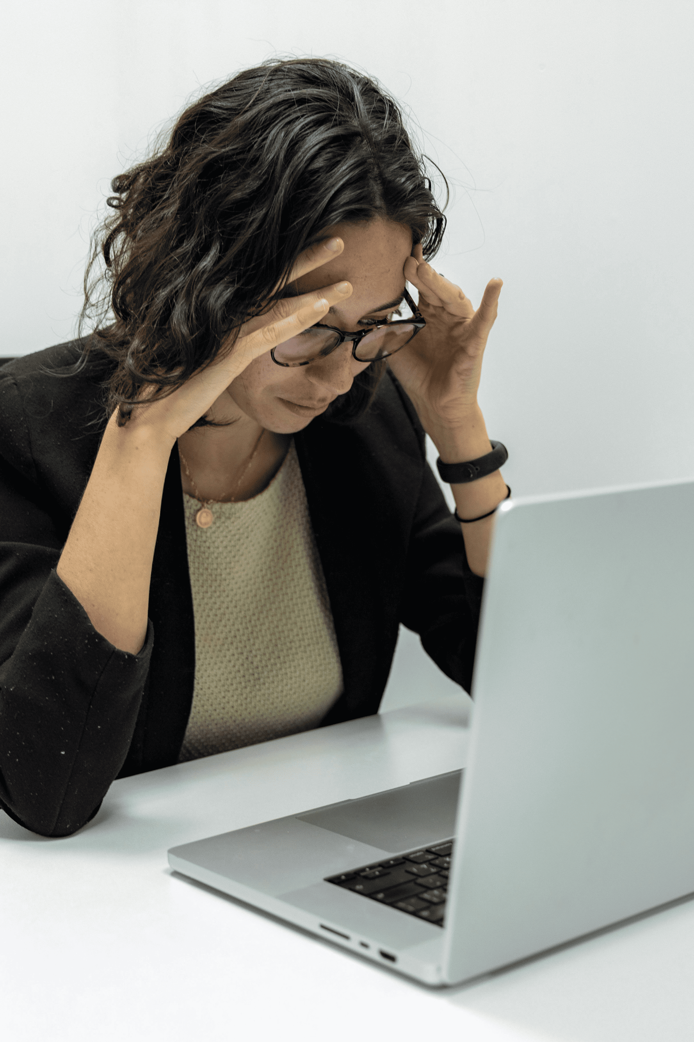 Woman sitting on couch holding her stomach in discomfort.