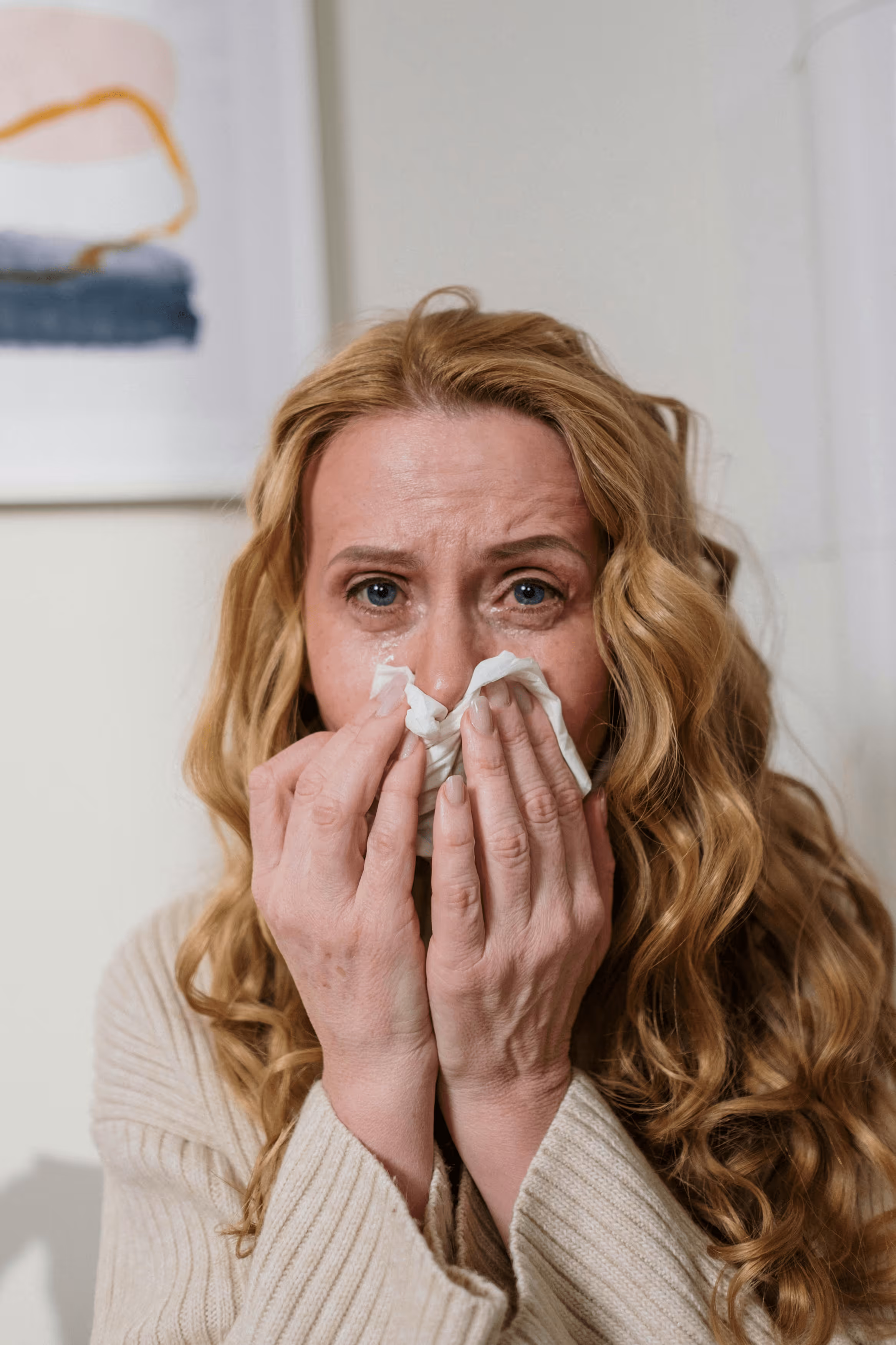 Woman sitting on couch holding her stomach in discomfort.