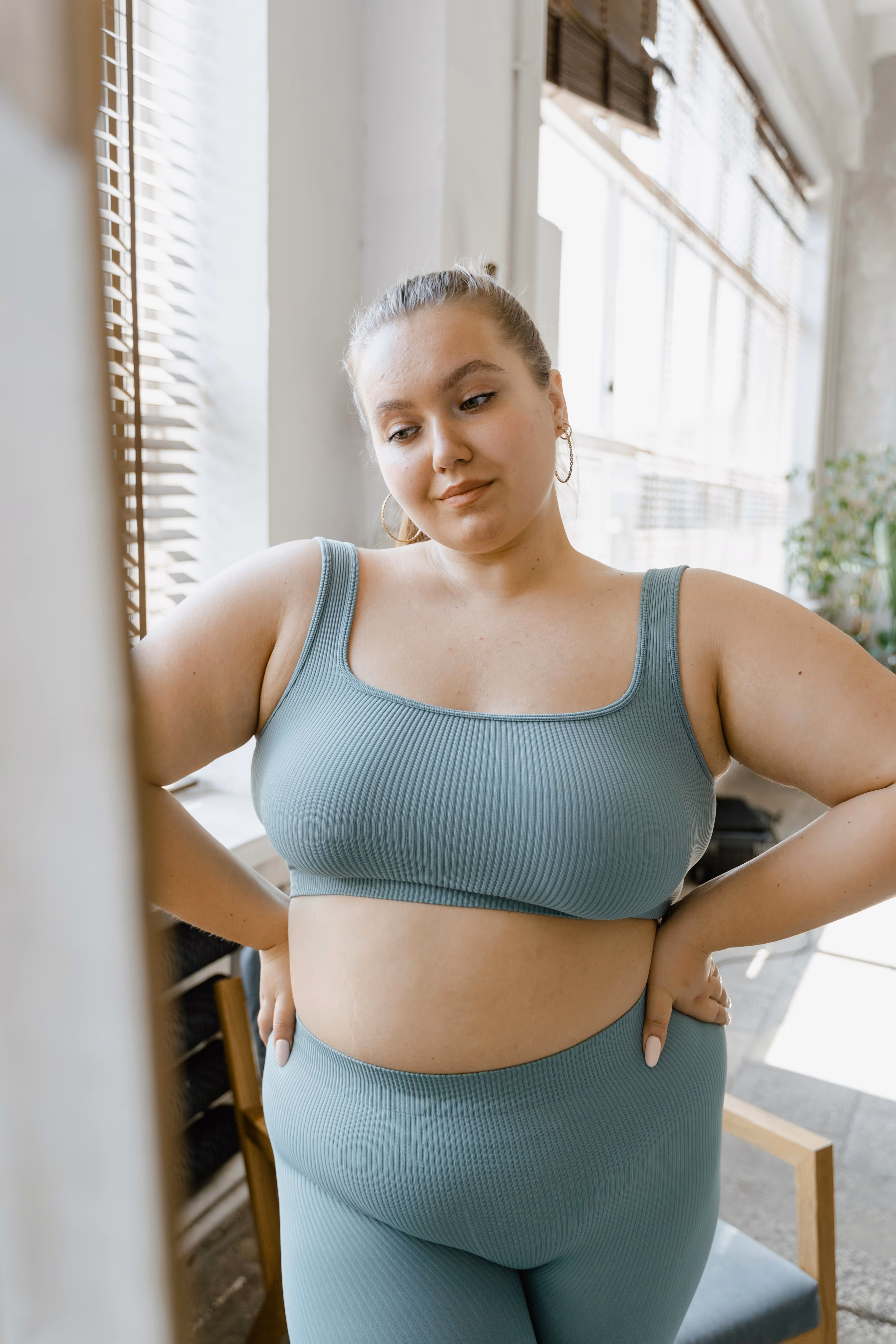 Woman sitting on couch holding her stomach in discomfort.
