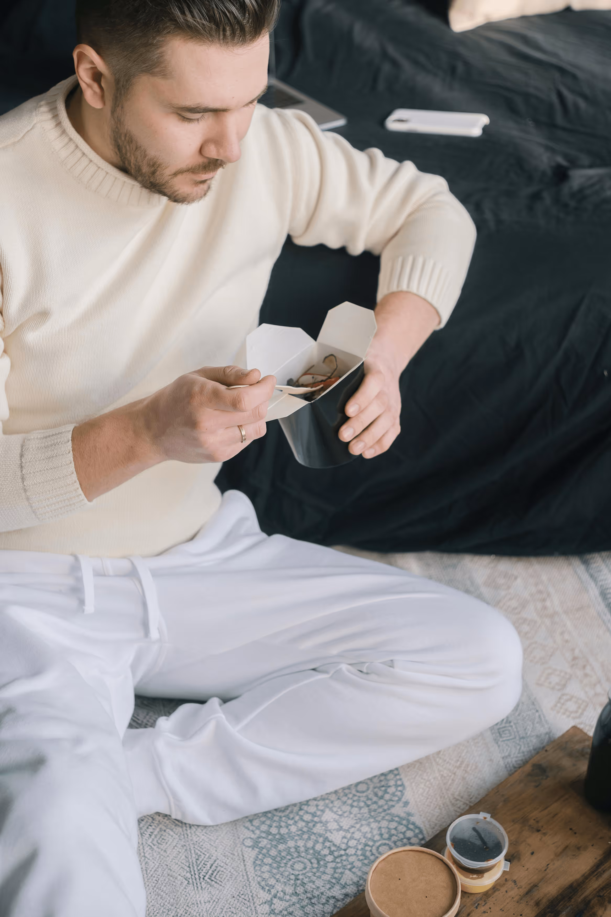 Woman sitting on couch holding her stomach in discomfort.