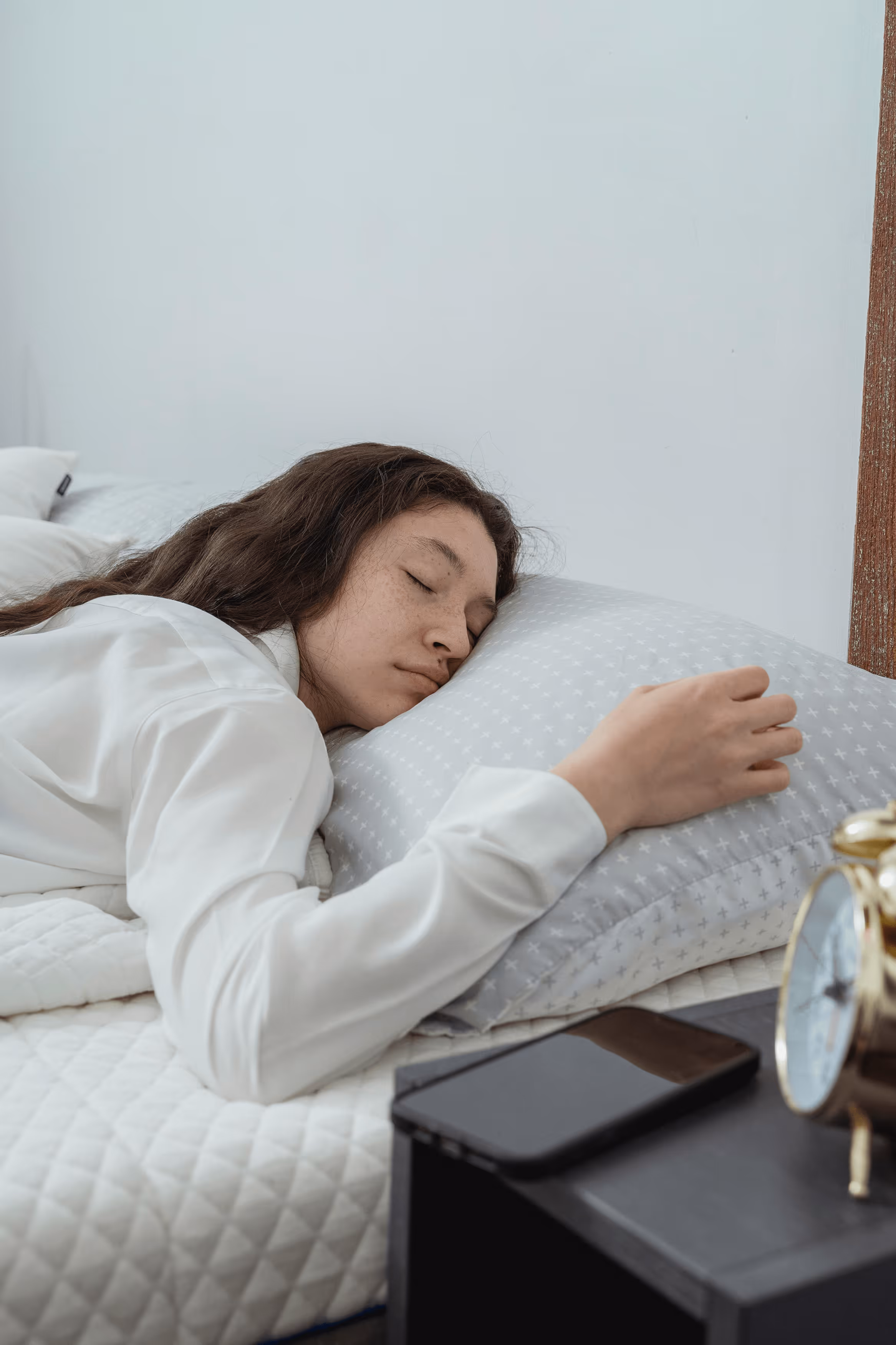 Woman sitting on couch holding her stomach in discomfort.