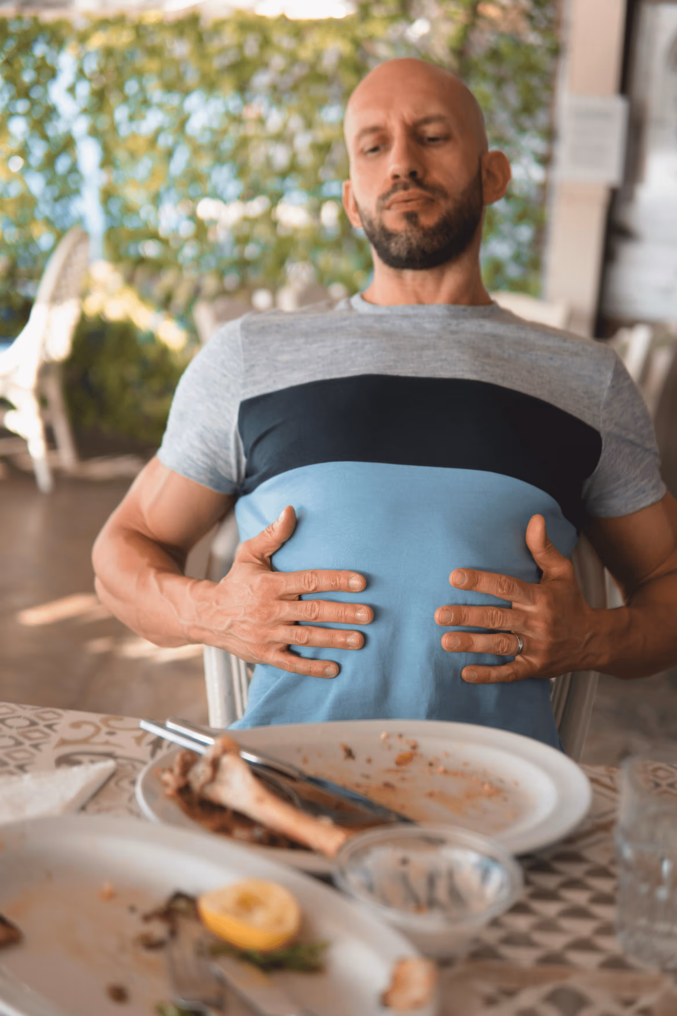 Woman sitting on couch holding her stomach in discomfort.