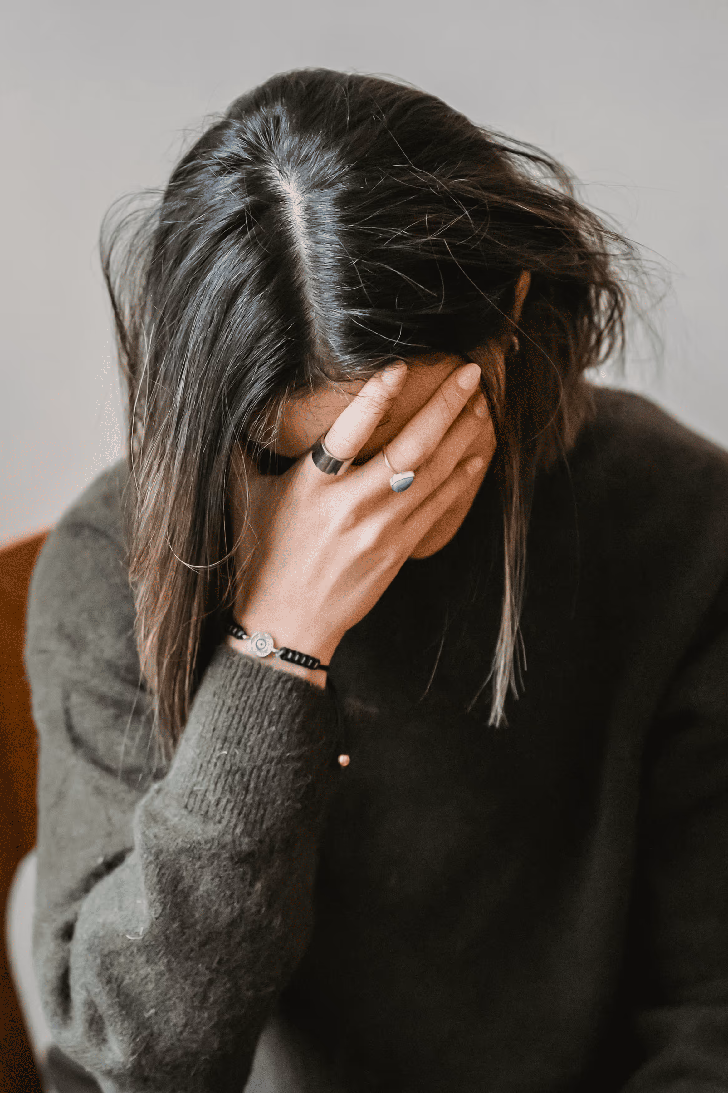 Woman sitting on couch holding her stomach in discomfort.