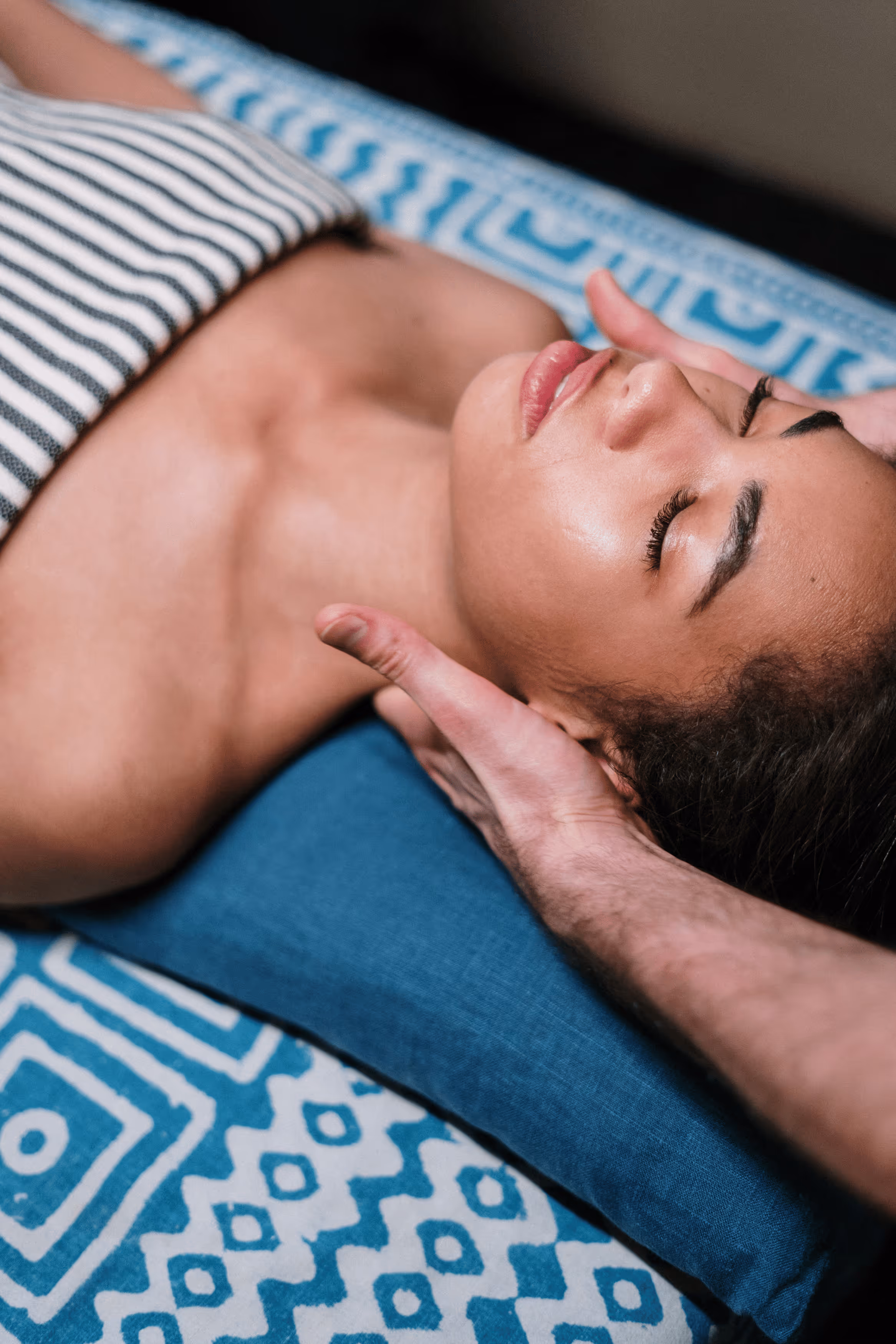 Woman sitting on couch holding her stomach in discomfort.