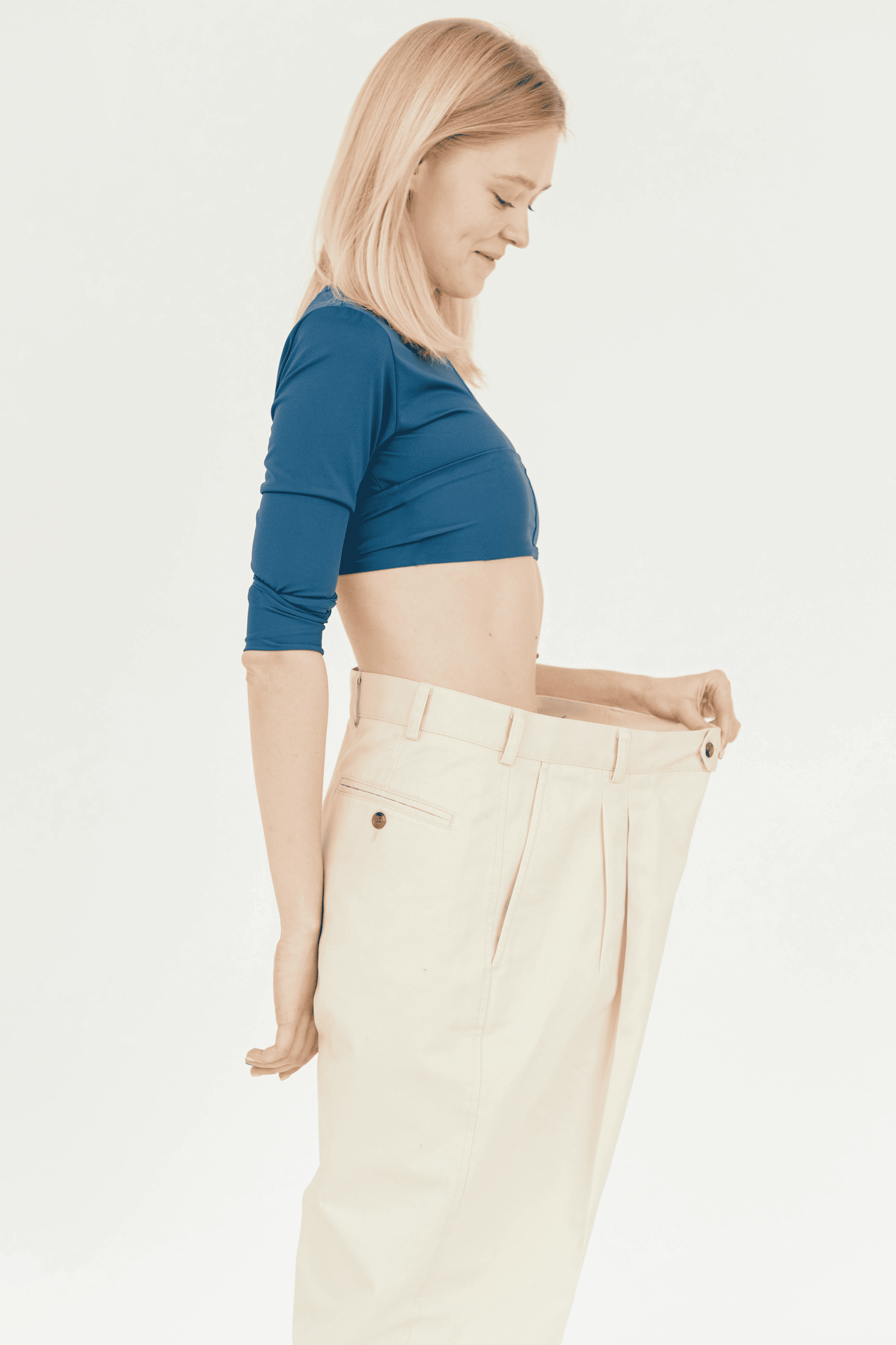 Woman sitting on couch holding her stomach in discomfort.