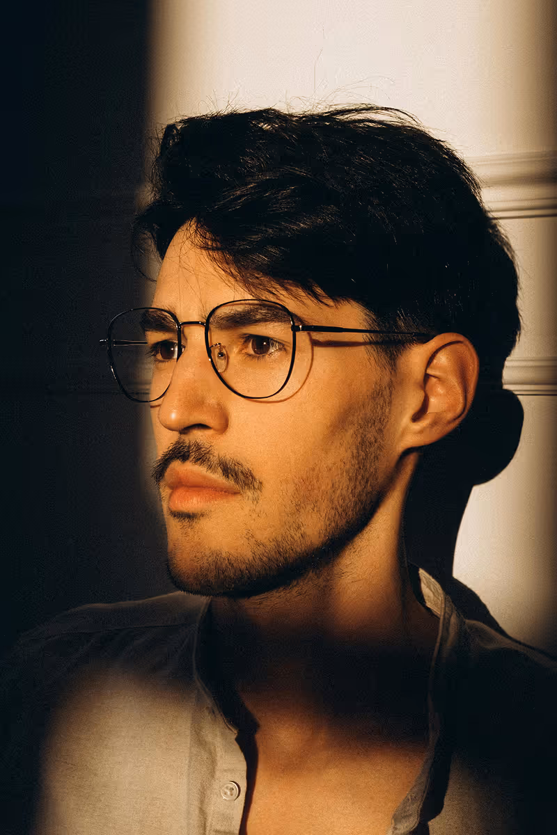 Man with dark hair and glasses looking confident after hair regrowth treatment by Hedfirst.
