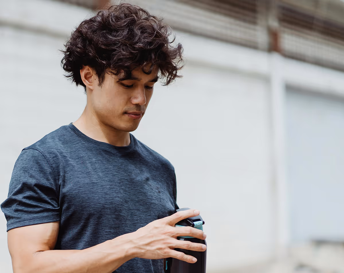 Man in athletic shirt looking at phone — personalized Hedfirst weight loss plan.