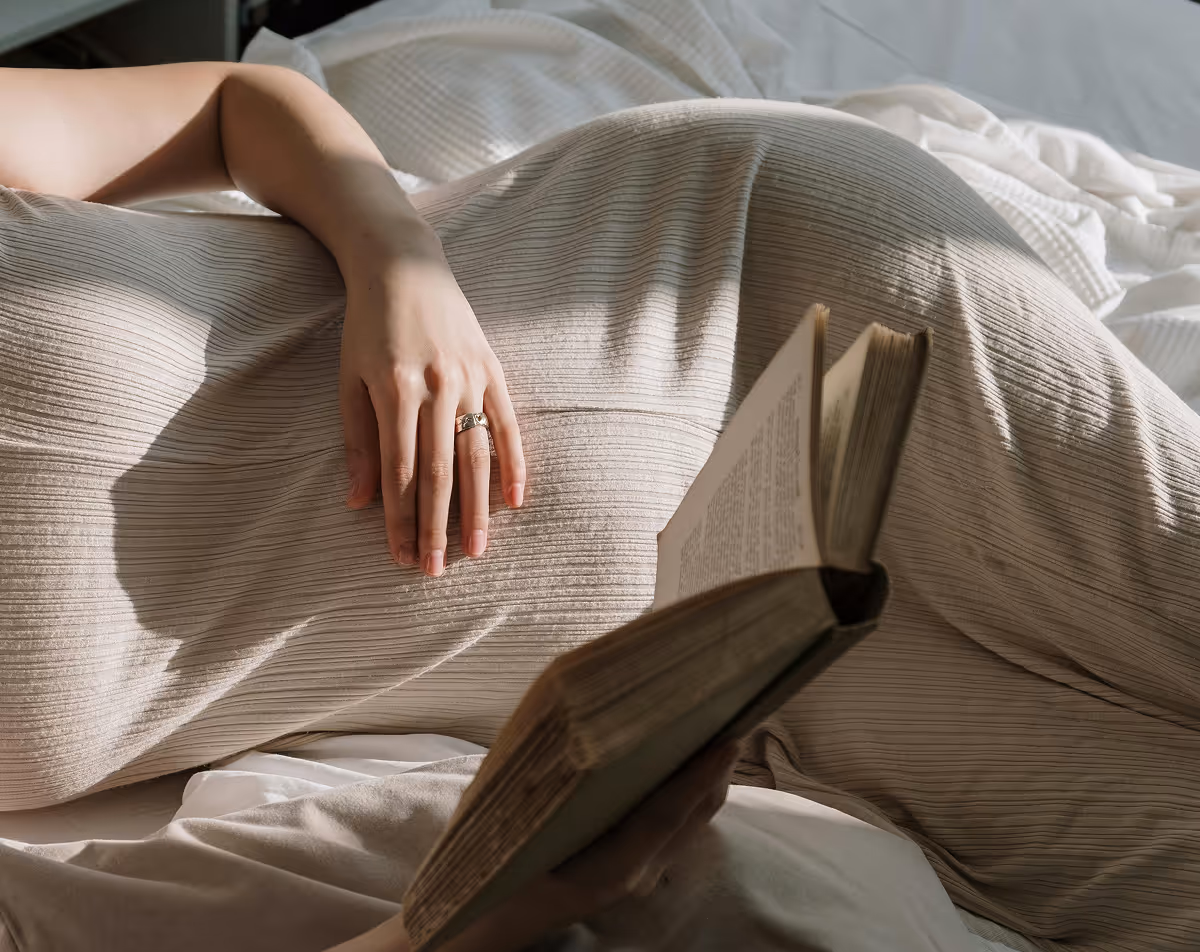 Close-up of woman’s hand with wedding ring resting on bed, symbolizing fertility and reproductive health.
