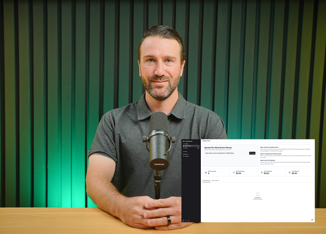 Man wearing a gray polo shirt sitting at a table with a microphone, with a screen showing a referral program dashboard beside him.