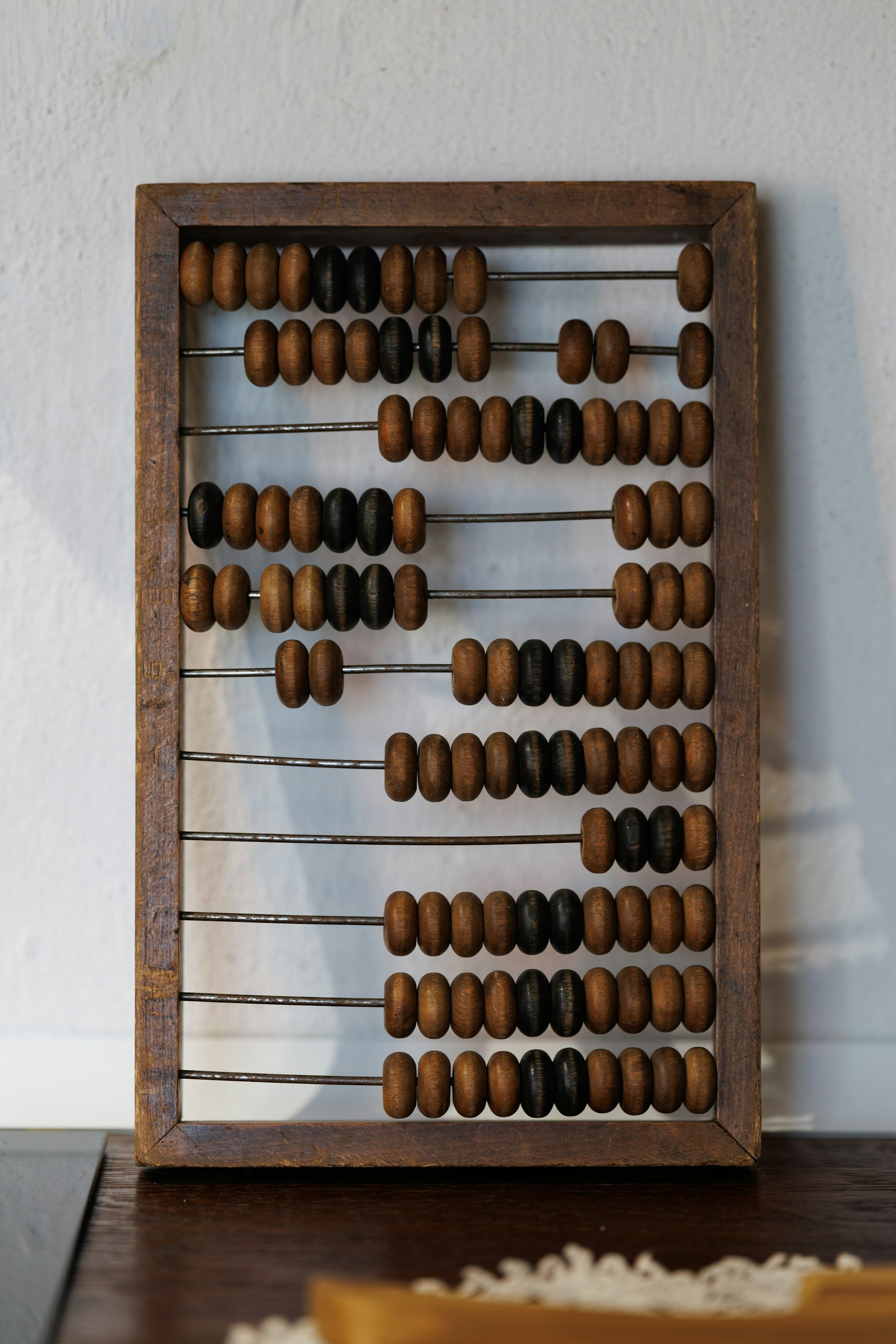 Vintage wooden abacus with brown beads on metal rods standing on a shelf