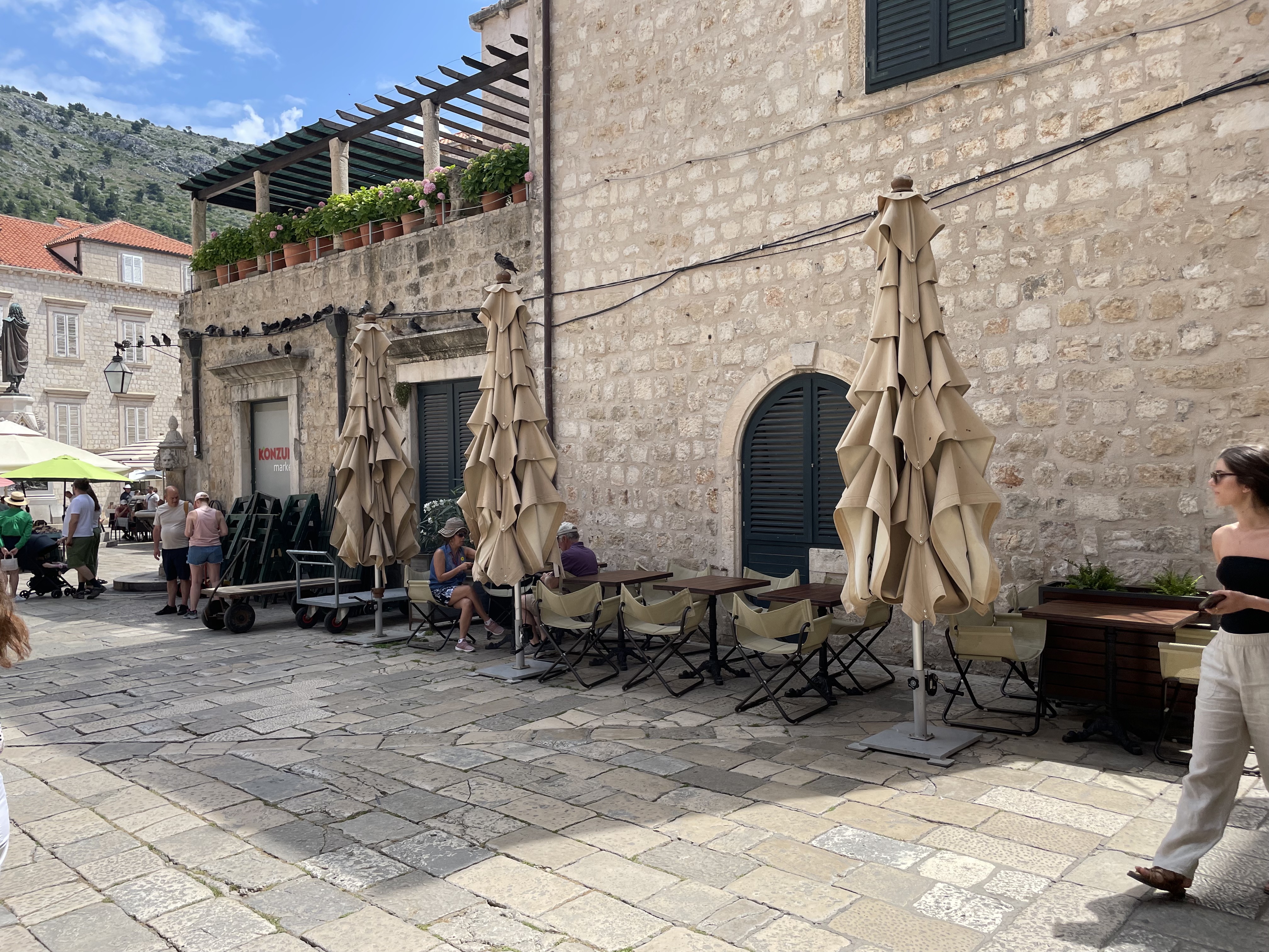 Outdoor café with folded umbrellas and empty tables on a cobblestone street.