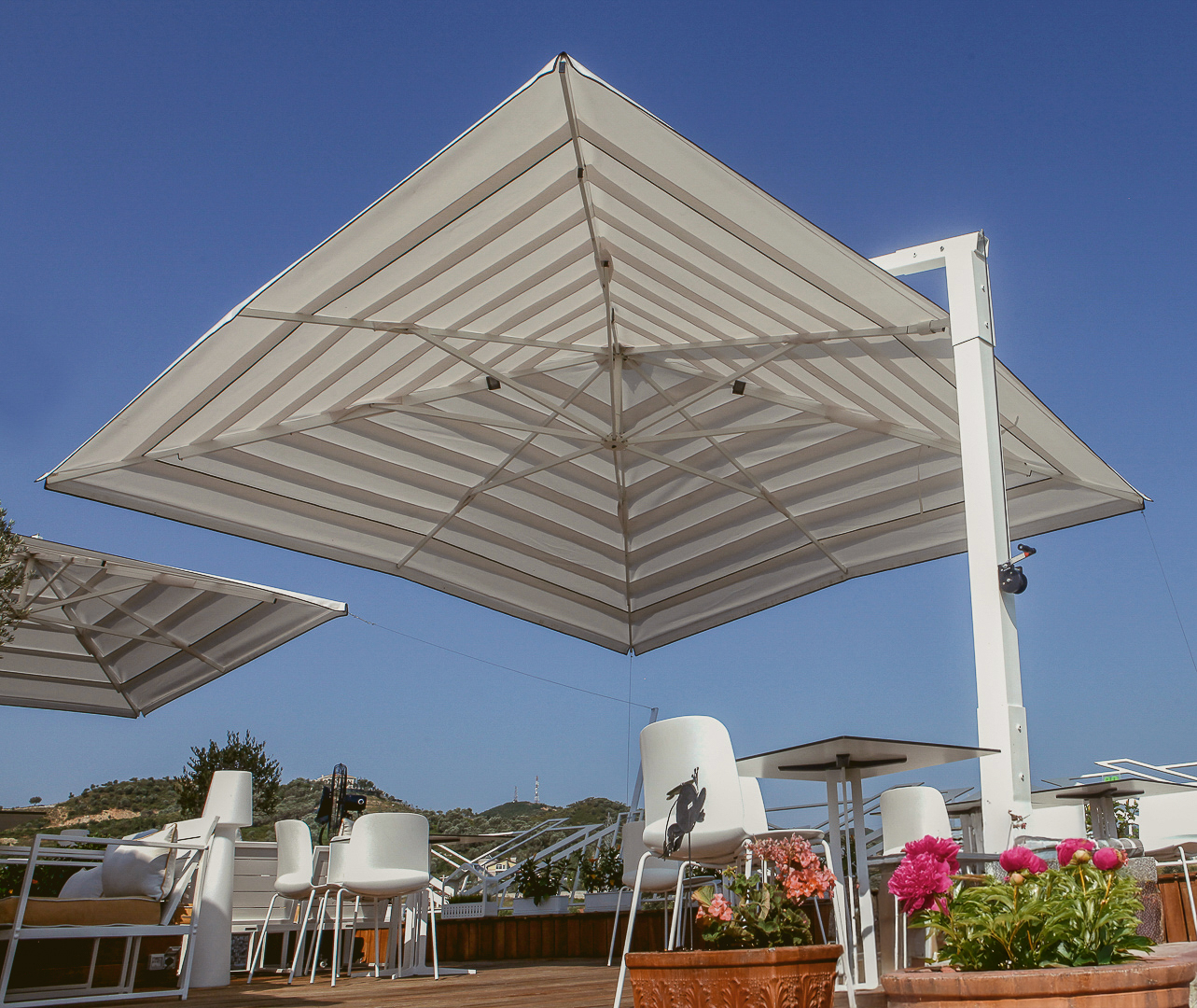 A large striped patio umbrella provides shade over a table and chairs on a sunny day.