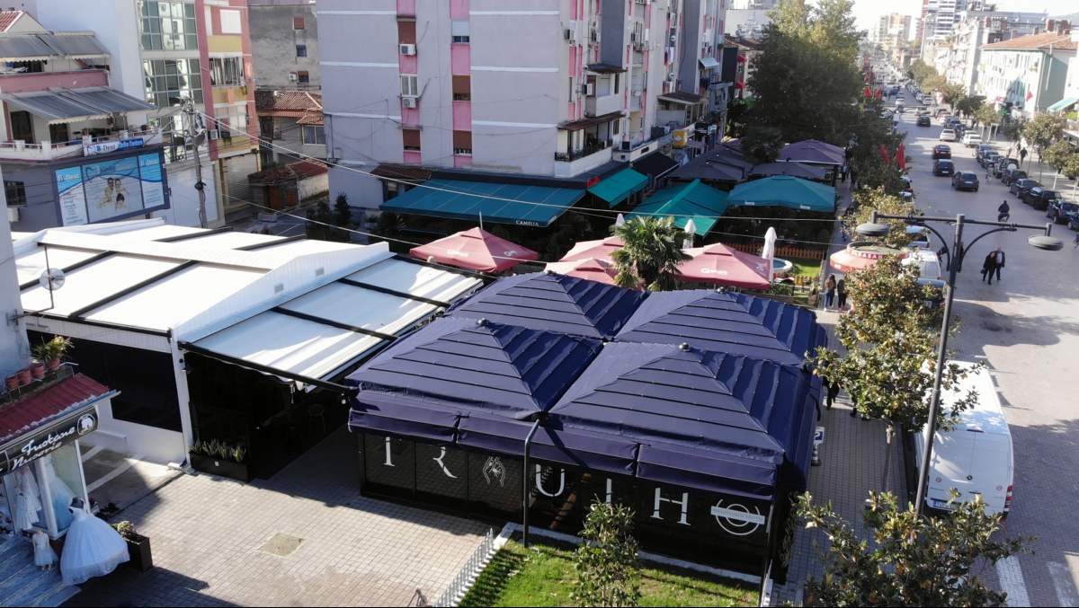 Street view showing outdoor seating areas with blue awnings and nearby colorful buildings.