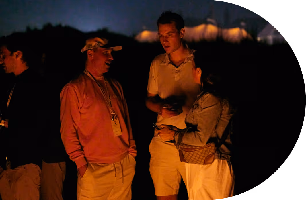 Four people chatting outdoors at night with warm light illuminating their faces.