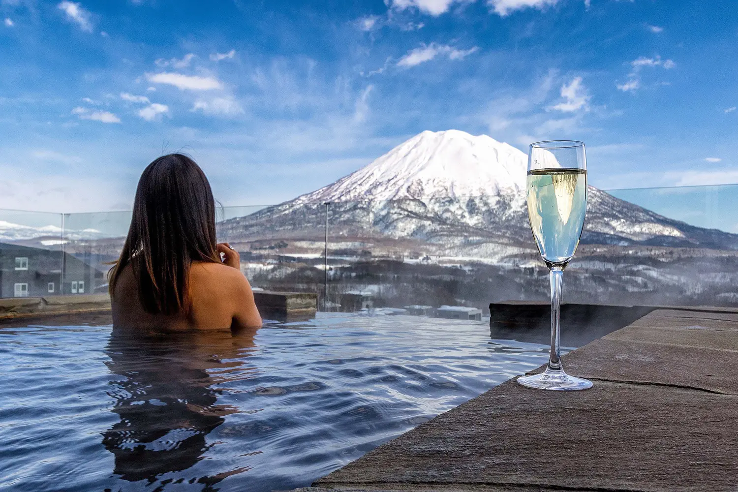 A woman sitting in a pool with a glass of wine.