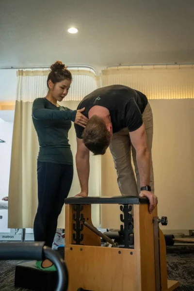 A man and a woman standing on top of a pilates machine.