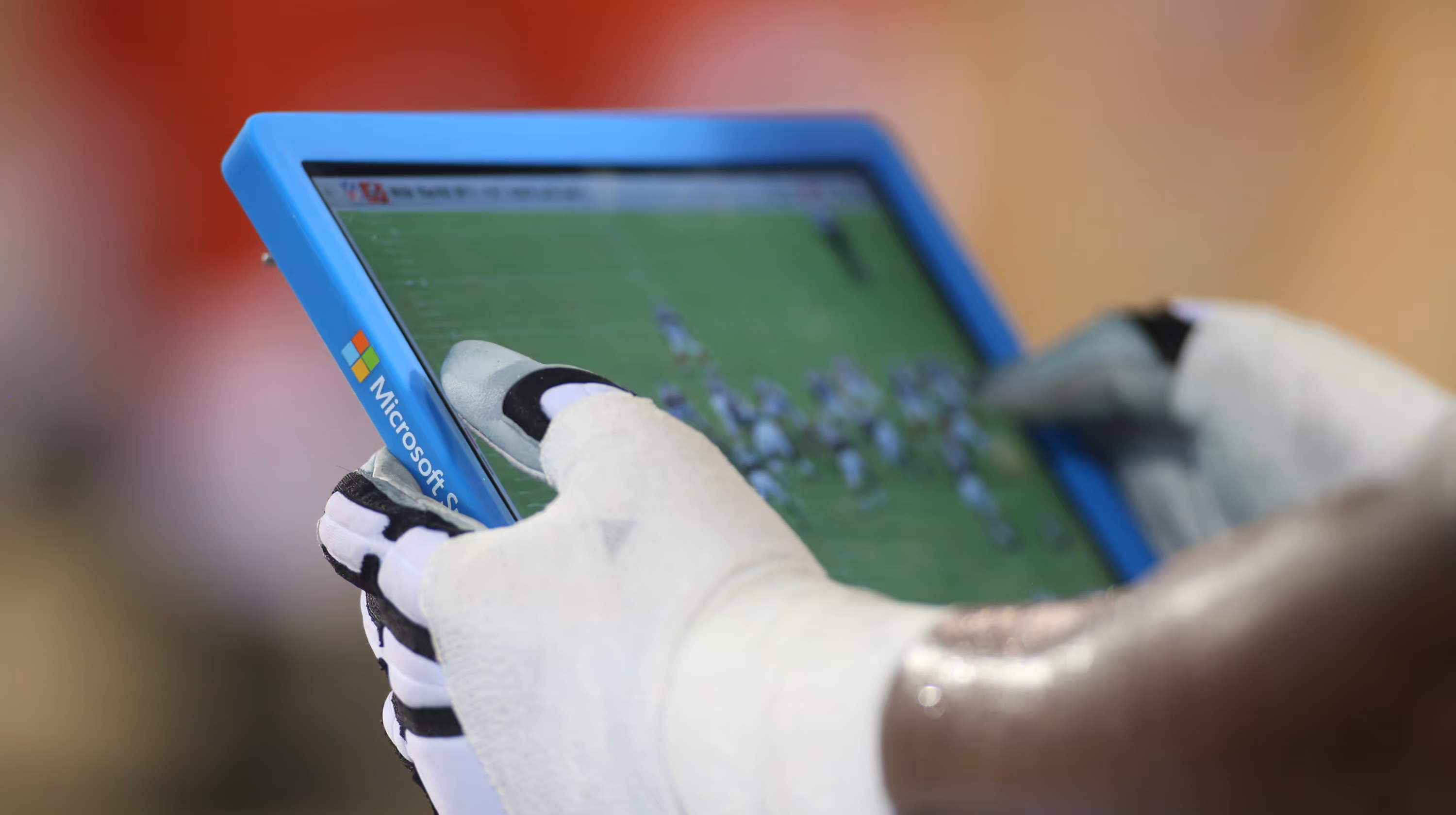 Football player using Microsoft Surface tablet on the sideline with Verizon app displaying game analysis