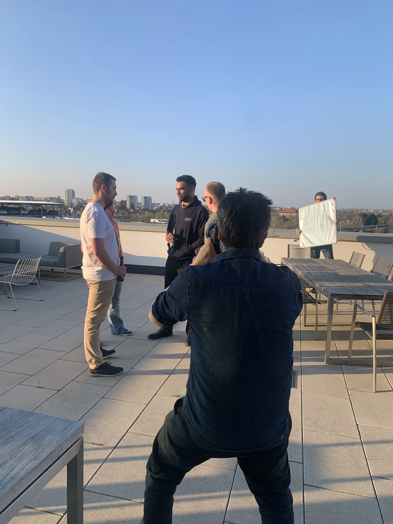 EIn Fotograf macht Imagebilder auf einer Dachterasse von einer Gruppe mit Leuten