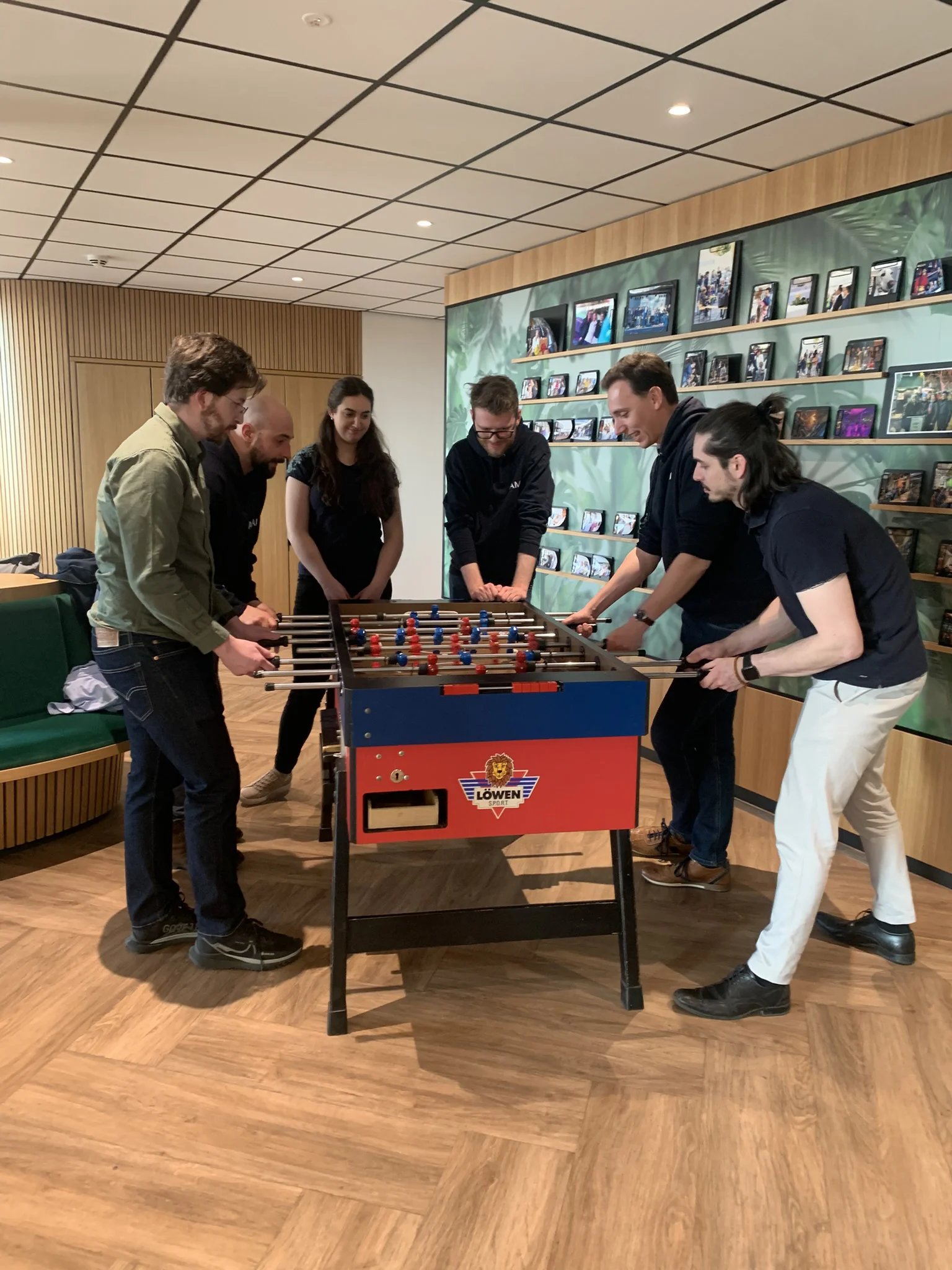 Eine Gruppe Leute an einem Tischkicker in einem Foyer