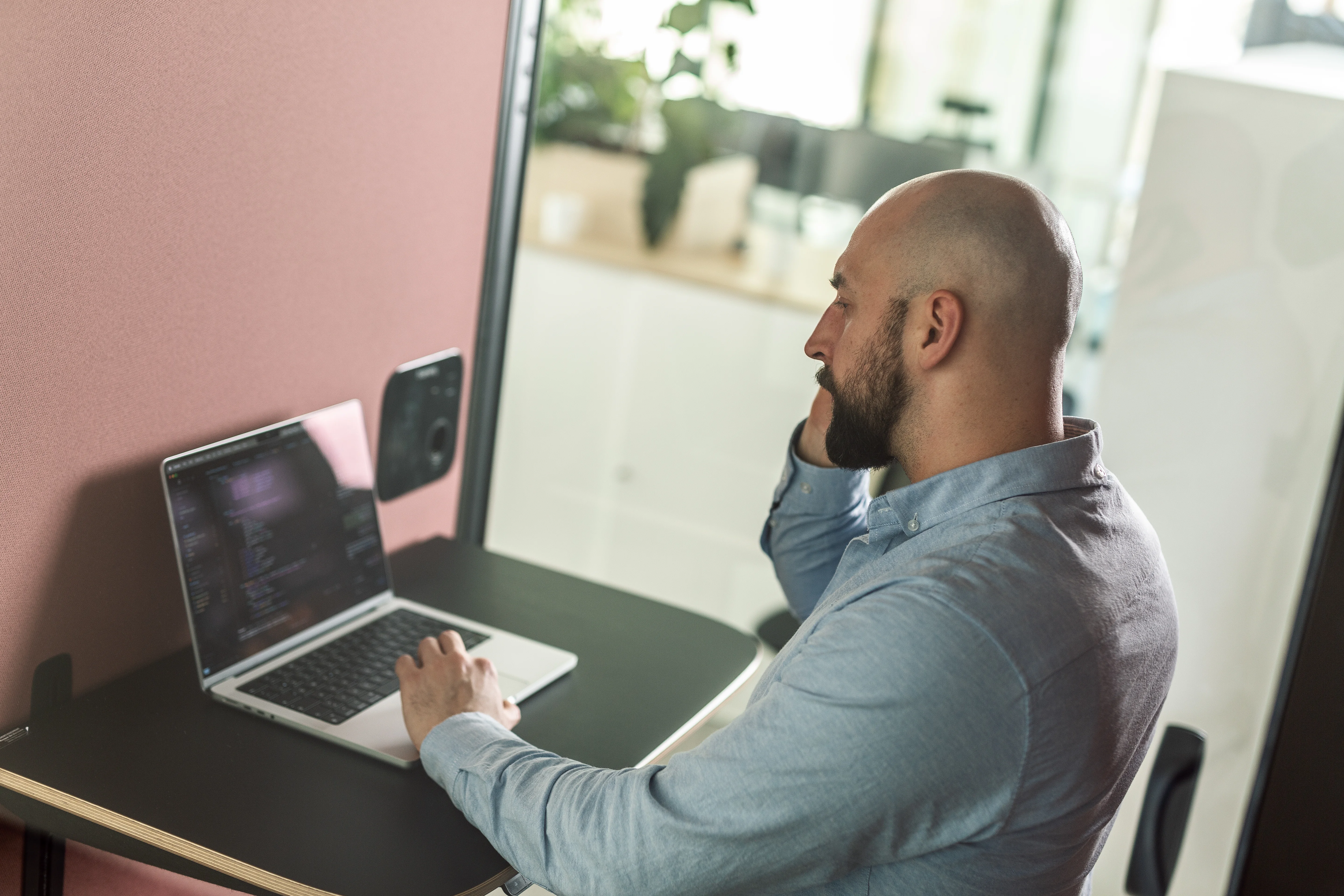 Ein Mensch arbeitet konzentriert am Laptop und telefoniert dabei