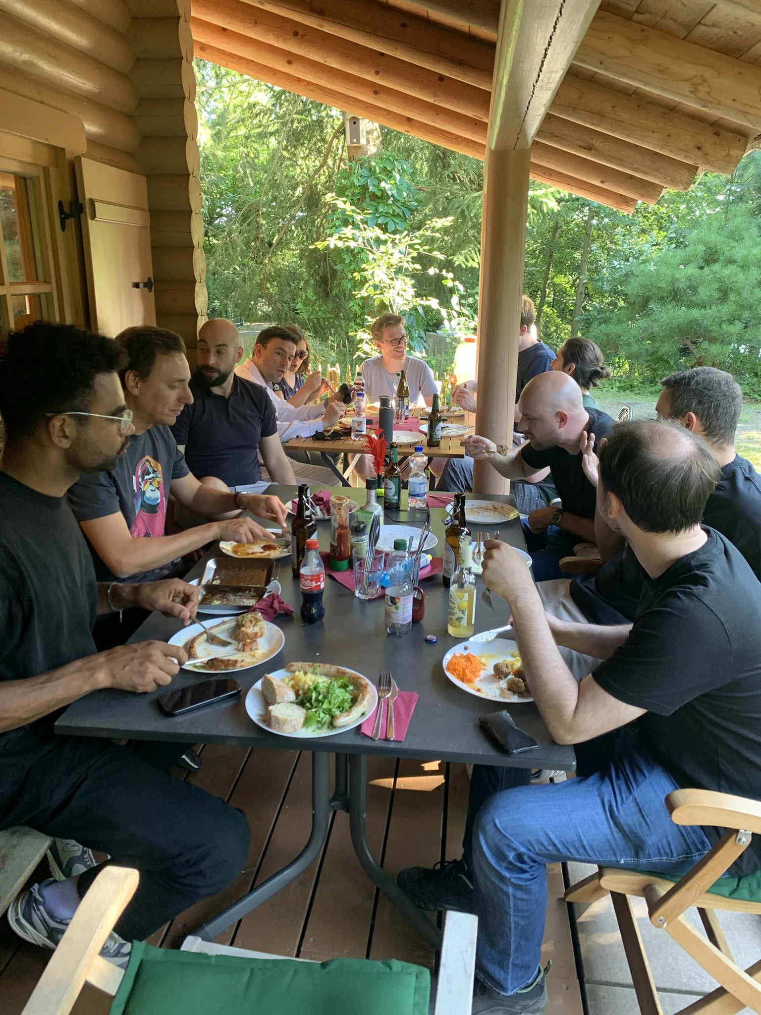 Eine Gruppe Leute an einem Tisch auf der Veranda einer Blockhütte beim Essen