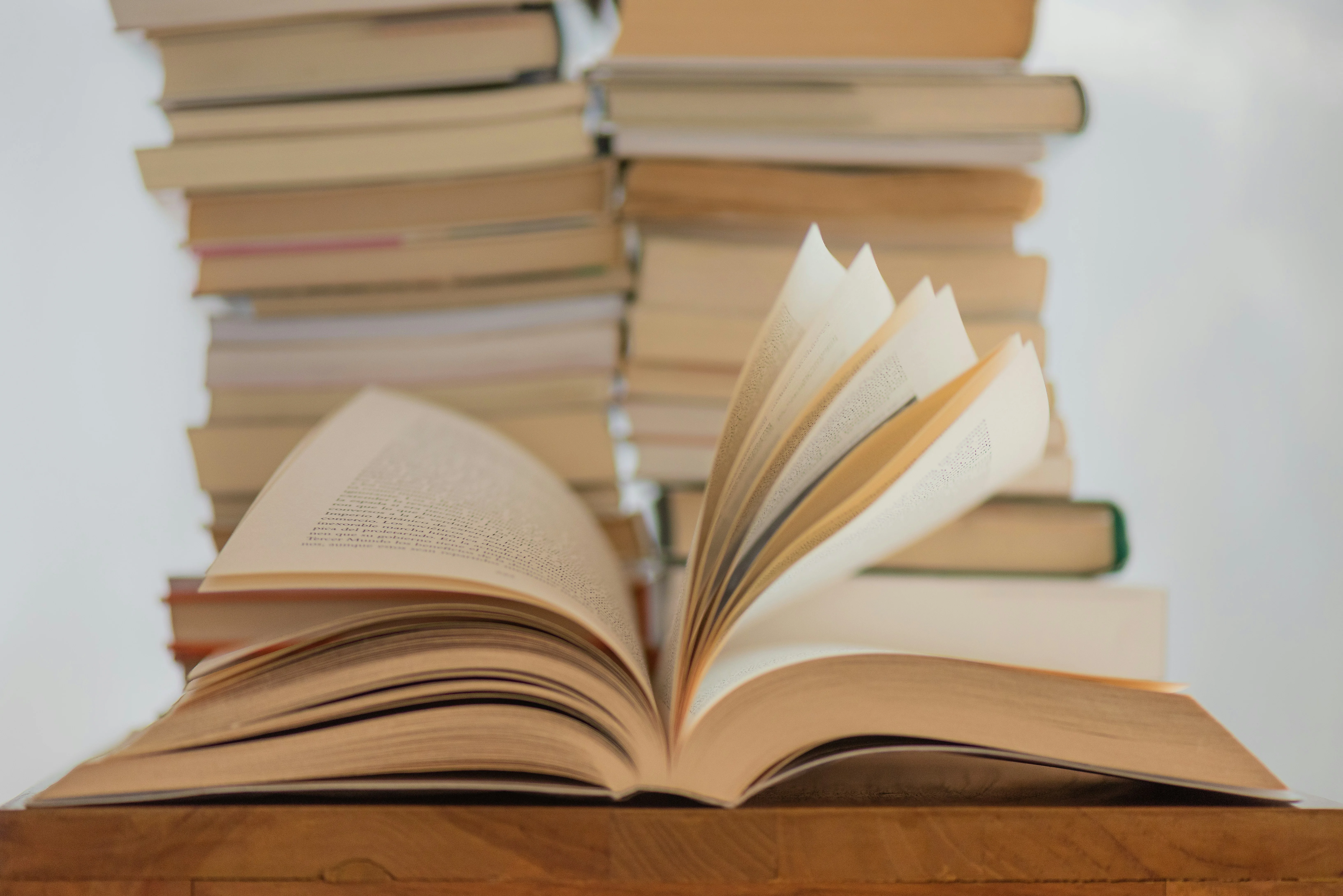 Ein aufgeschlagenes Buch vor einem Bücherstapel