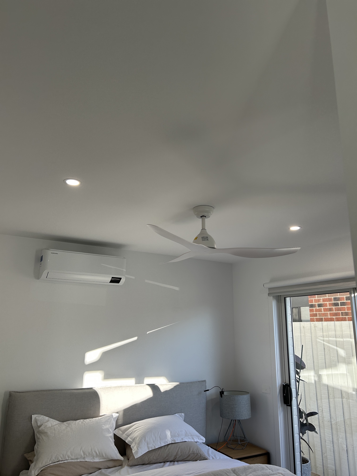 Modern bedroom with a ceiling fan and downlights installed by Ferguson Electrical in Edithvale.