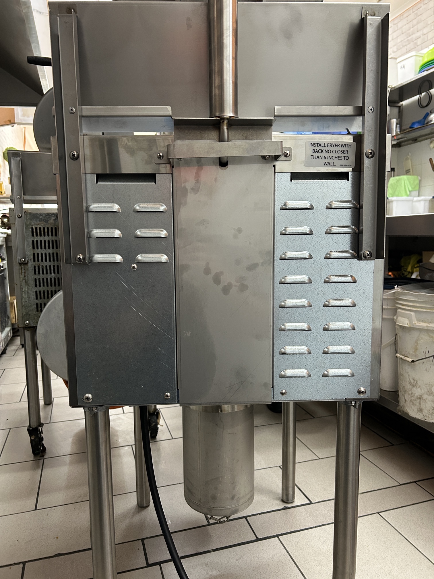Electrician installing a 3-phase pressure fryer in a Clayton commercial kitchen with compliant flexible lead and isolator.