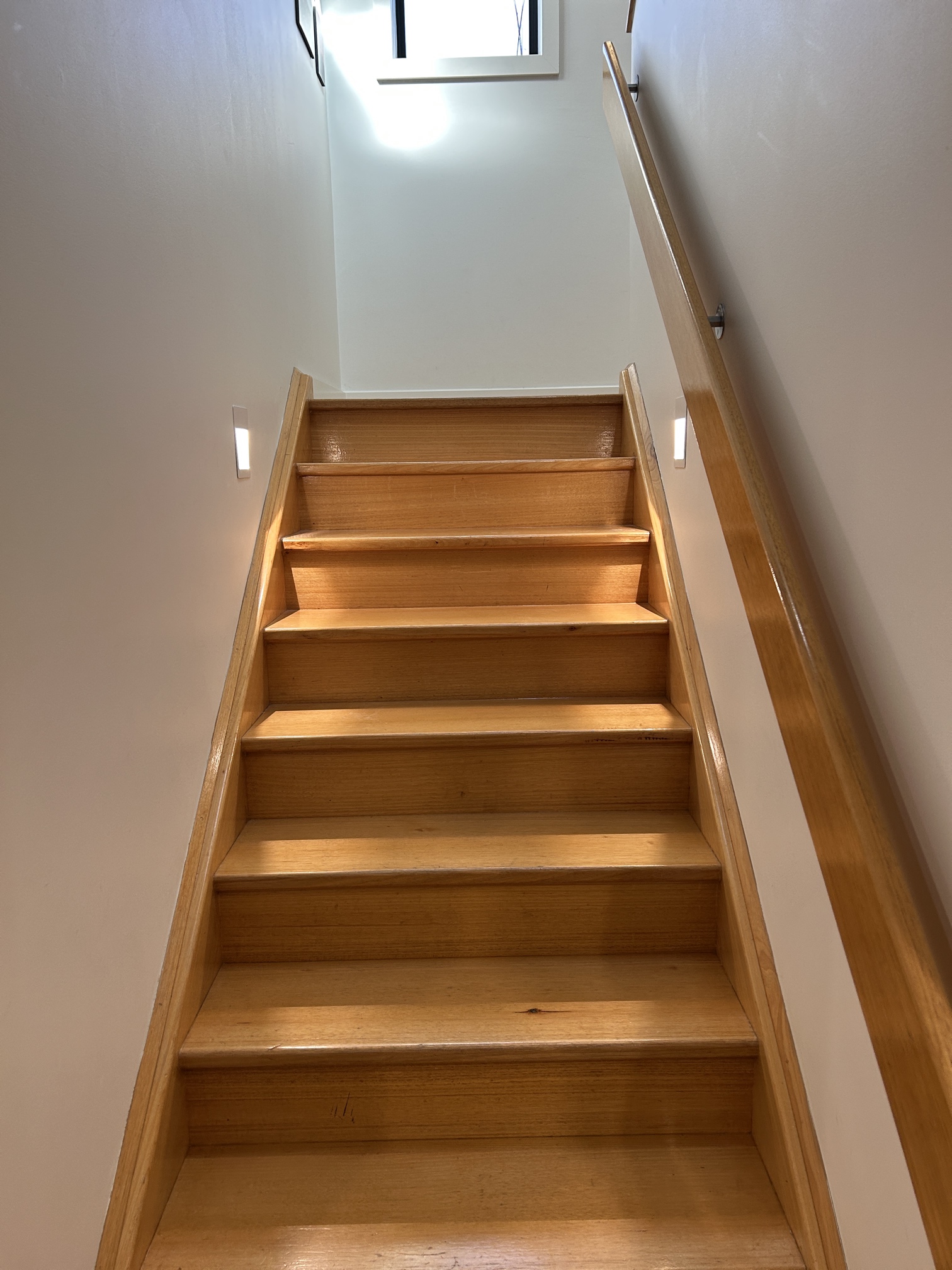 Custom LED stair lights installed along a timber staircase in a Windsor home, fitted seamlessly into existing wall cutouts.