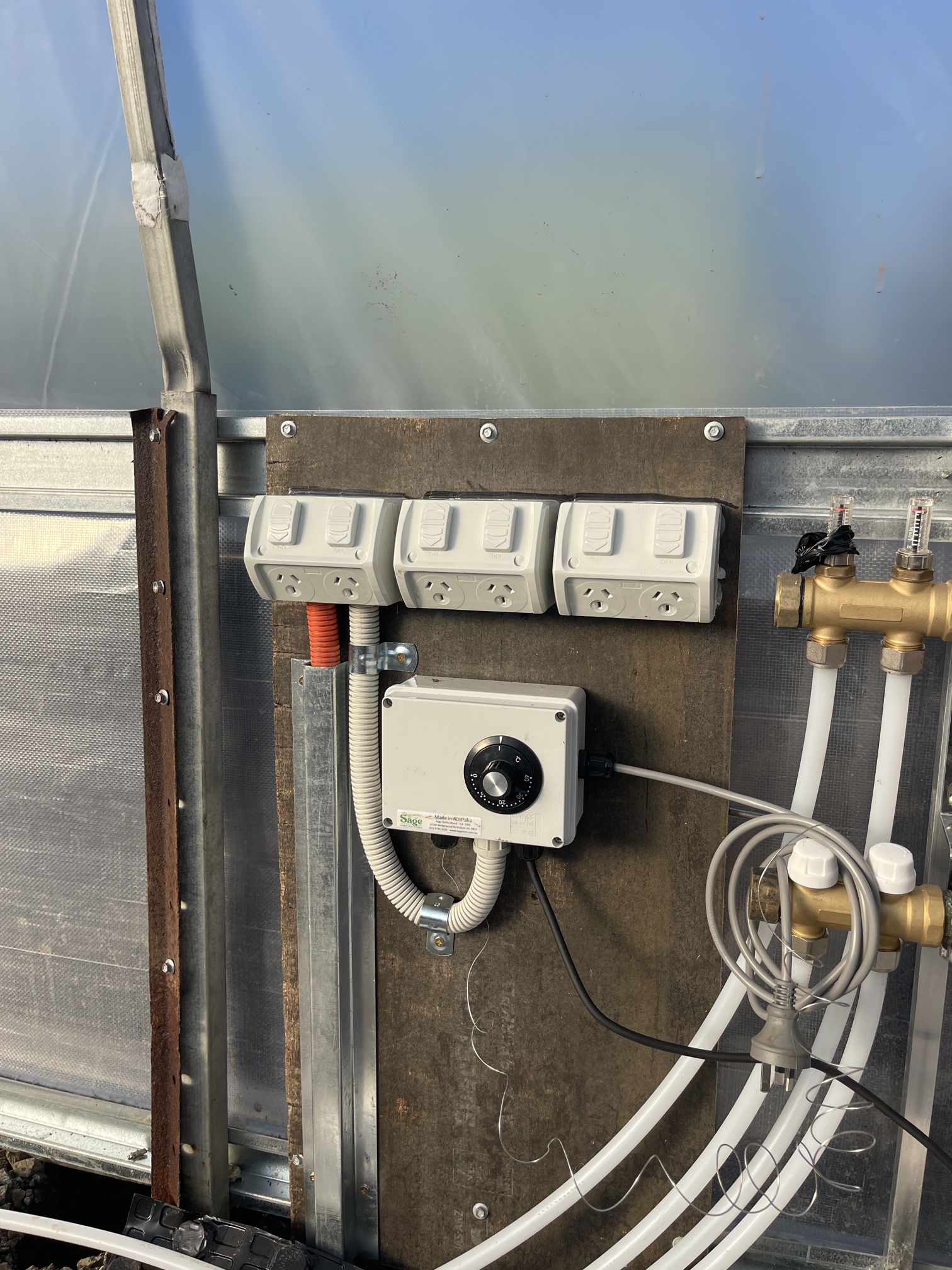 Commercial electrical installation in Bangholme showing underground power trench and weatherproof power outlets for a greenhouse and hydronic pump system by Ferguson Electrical.