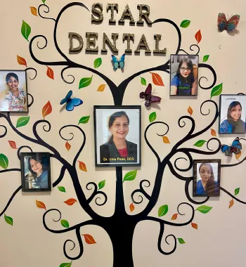 Wall display of a black tree with colorful leaves and butterflies surrounding framed photos of dental staff under the title 'Star Dental'.