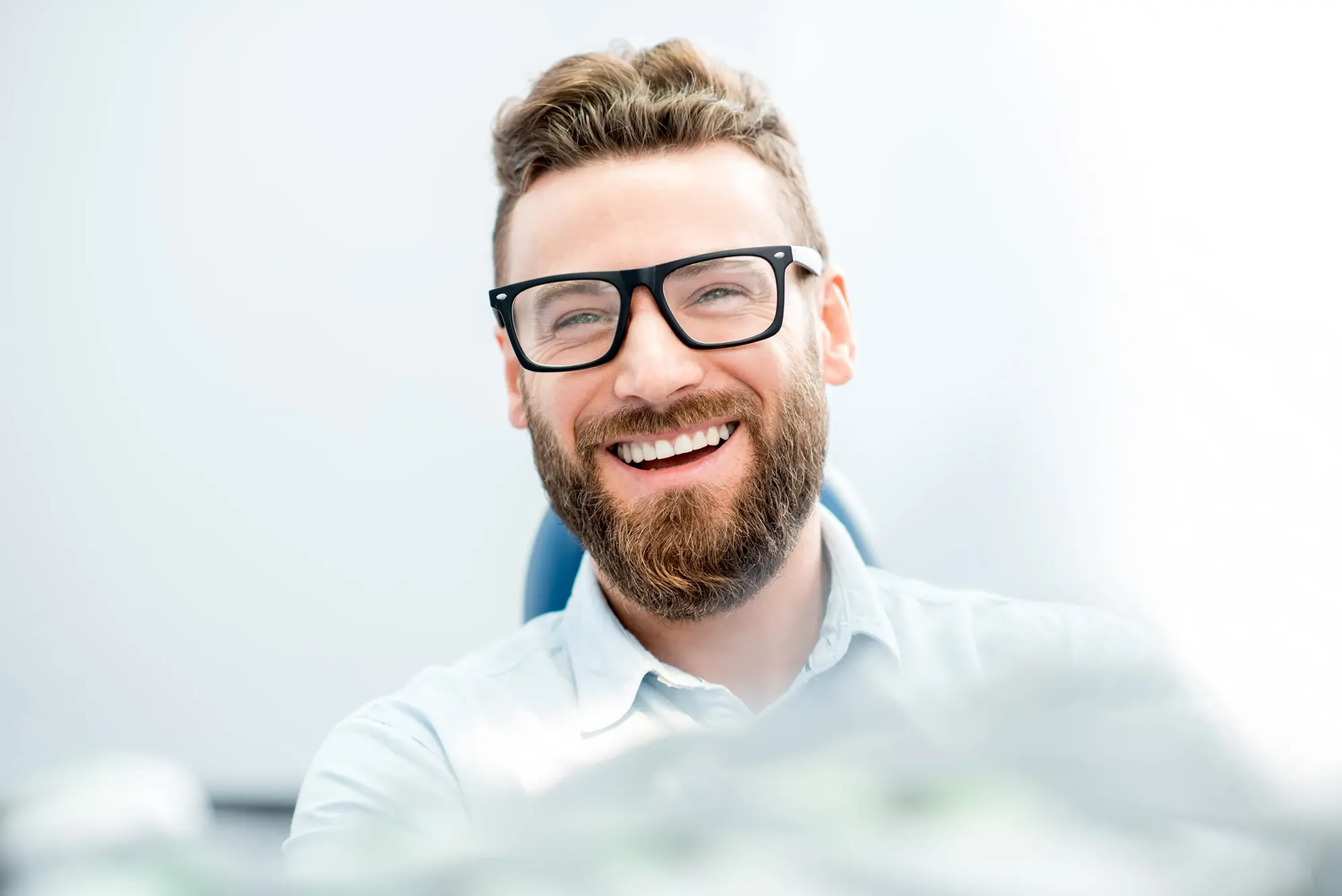 Smiling man with glasses and a beard in a dental office