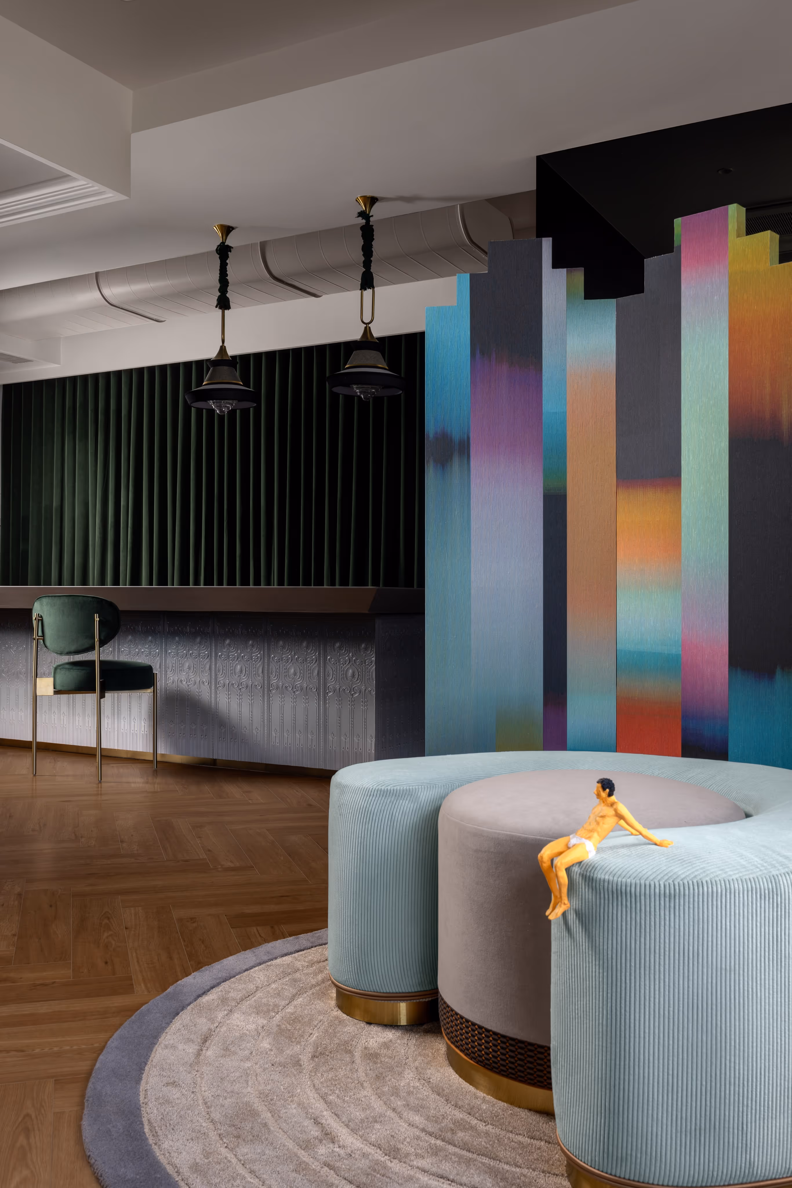 A living room with a round couch and a colorful wall.
