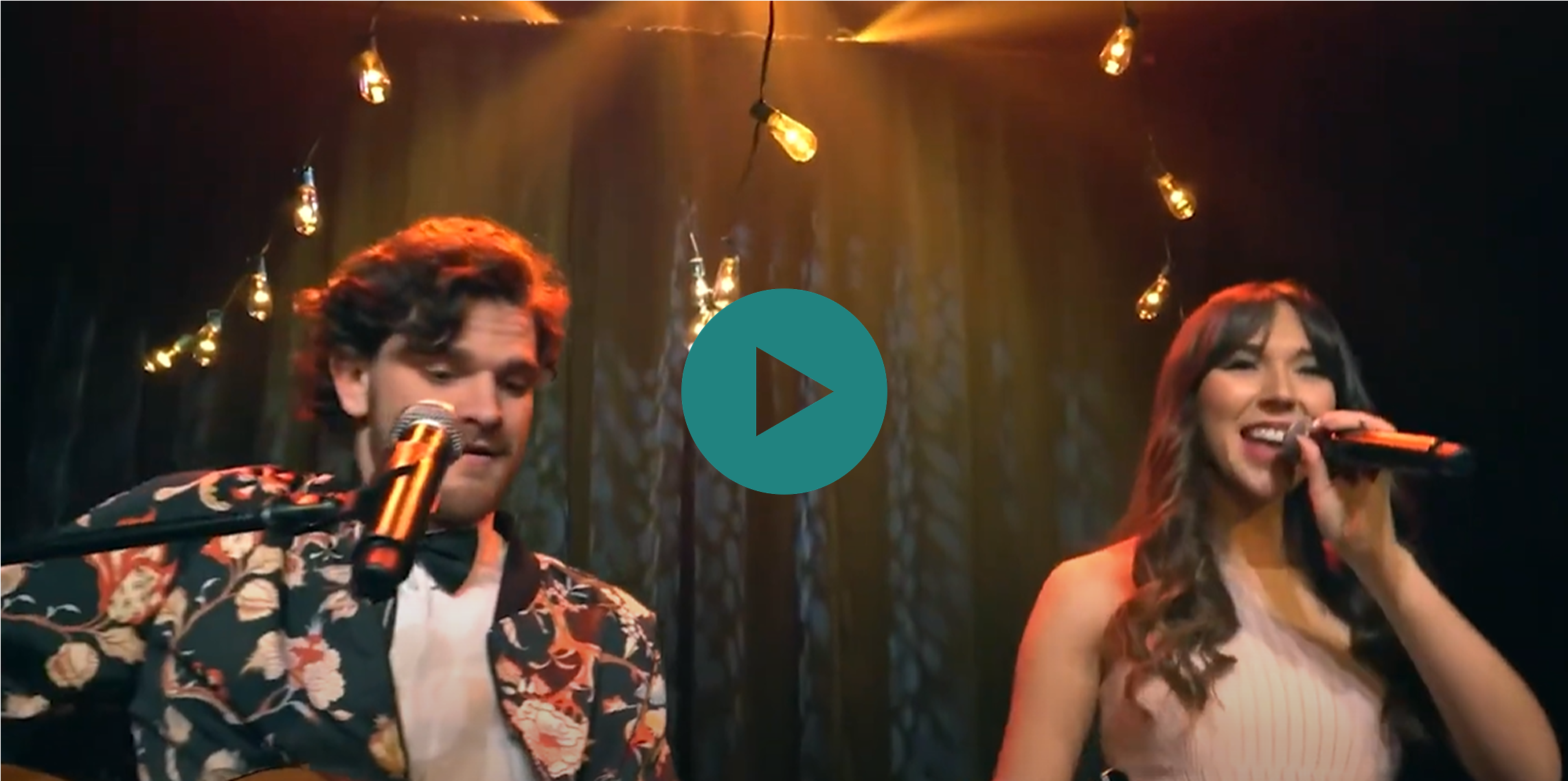 A man and a woman singing in front of a green screen.