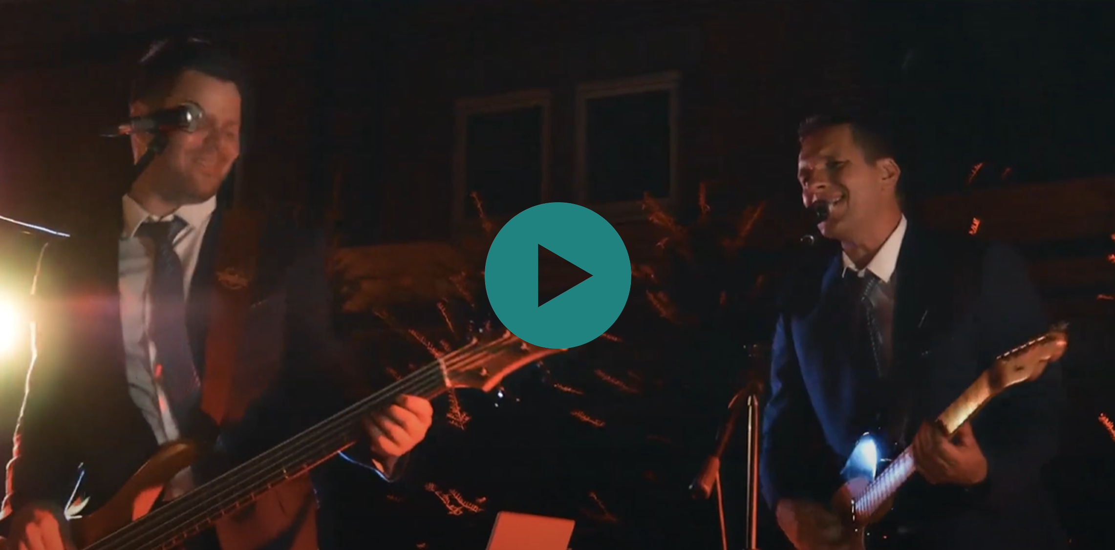 A man playing a guitar with a video playing in the background.