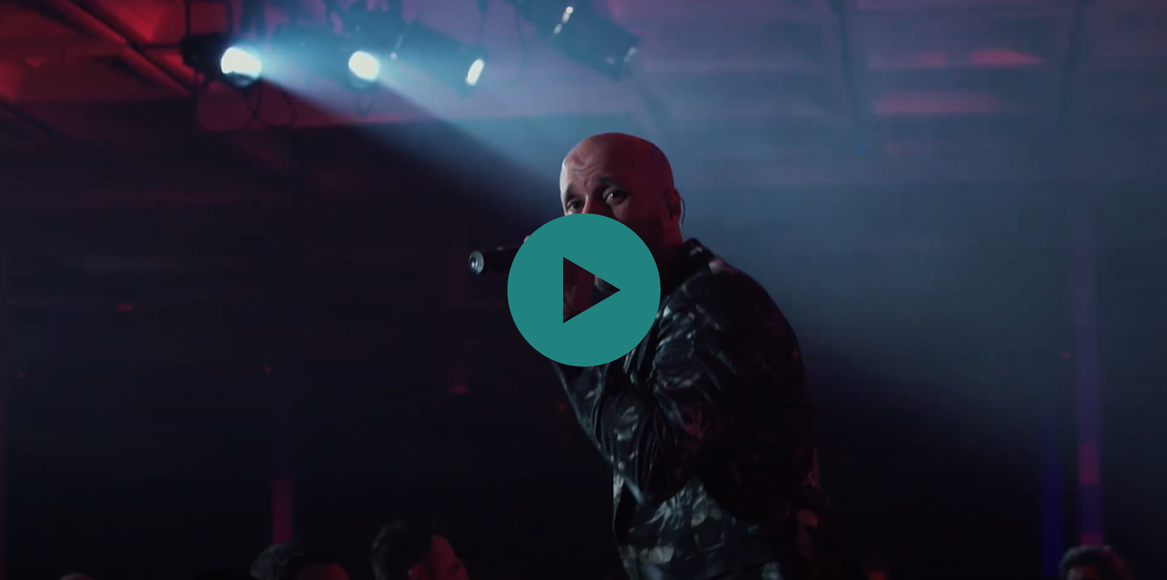 A man singing into a microphone with a green play button on the screen.