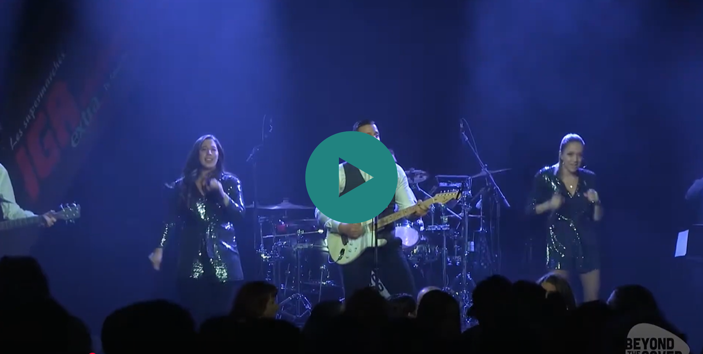 A man plays a guitar on stage while a woman sings.