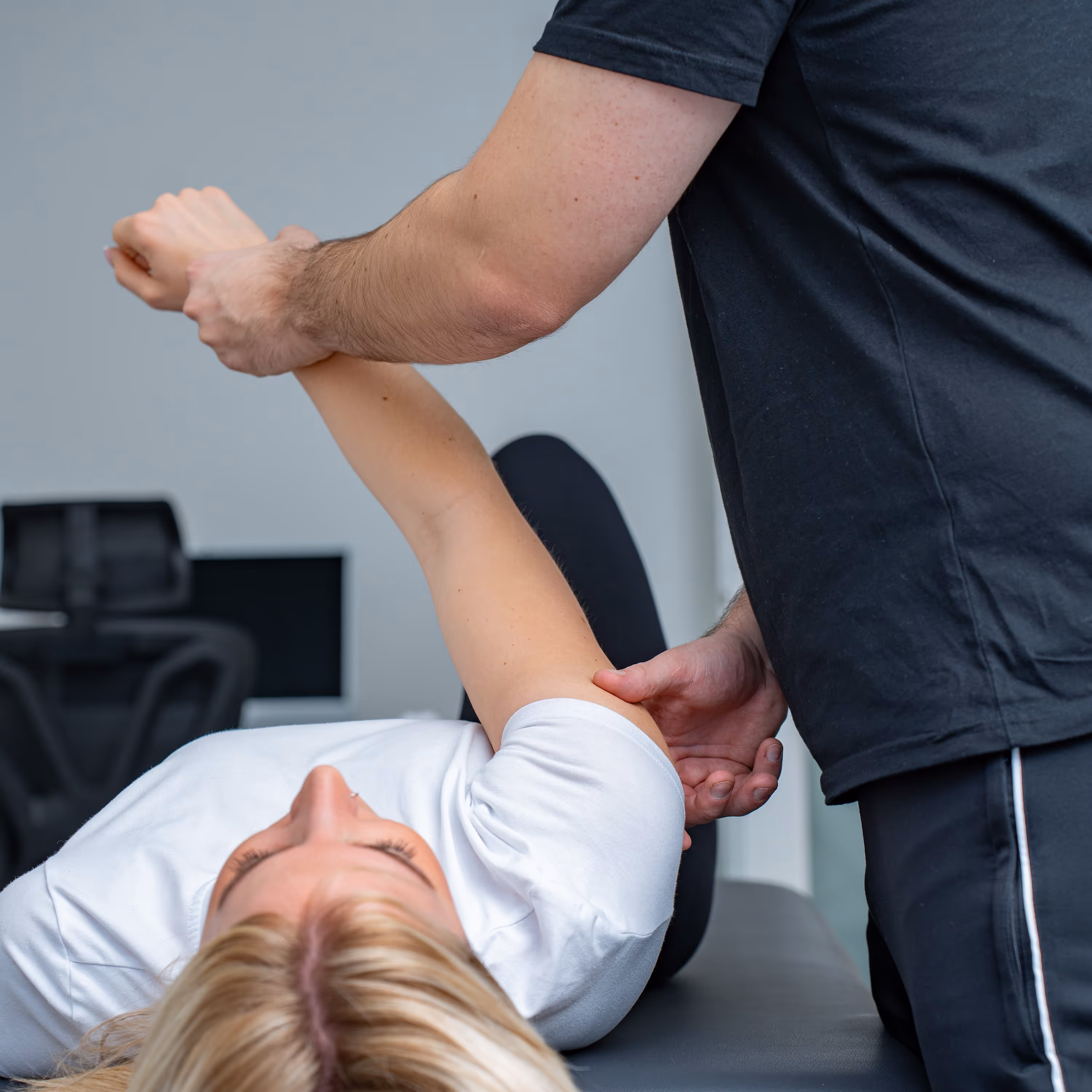 Ein Physiotherapeut therapiert eine junge Frau.