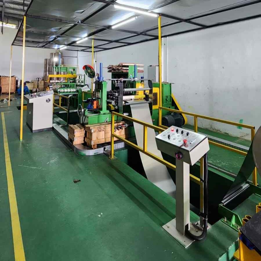 Industrial machine in a factory producing a continuous sheet of material with control panels and green and yellow safety railings.