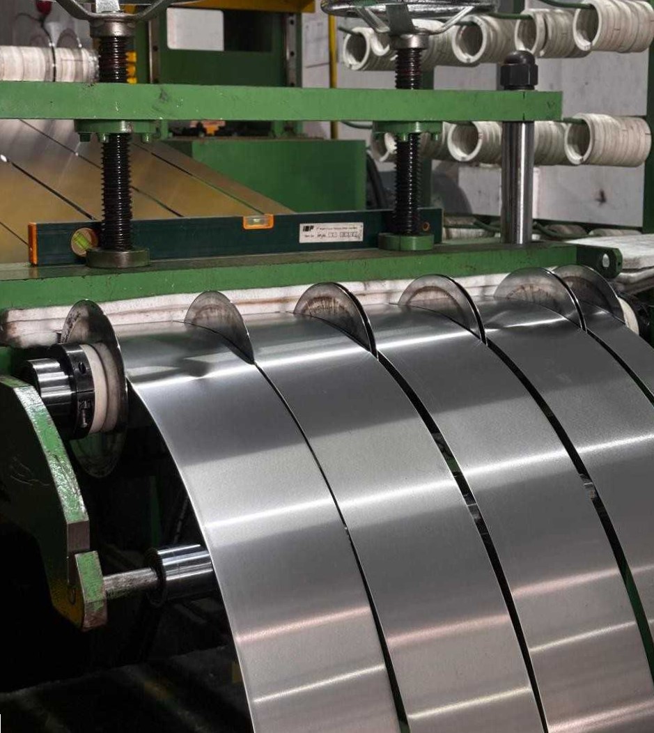 Industrial machine with multiple shiny metal strips being sliced and wound around rollers.