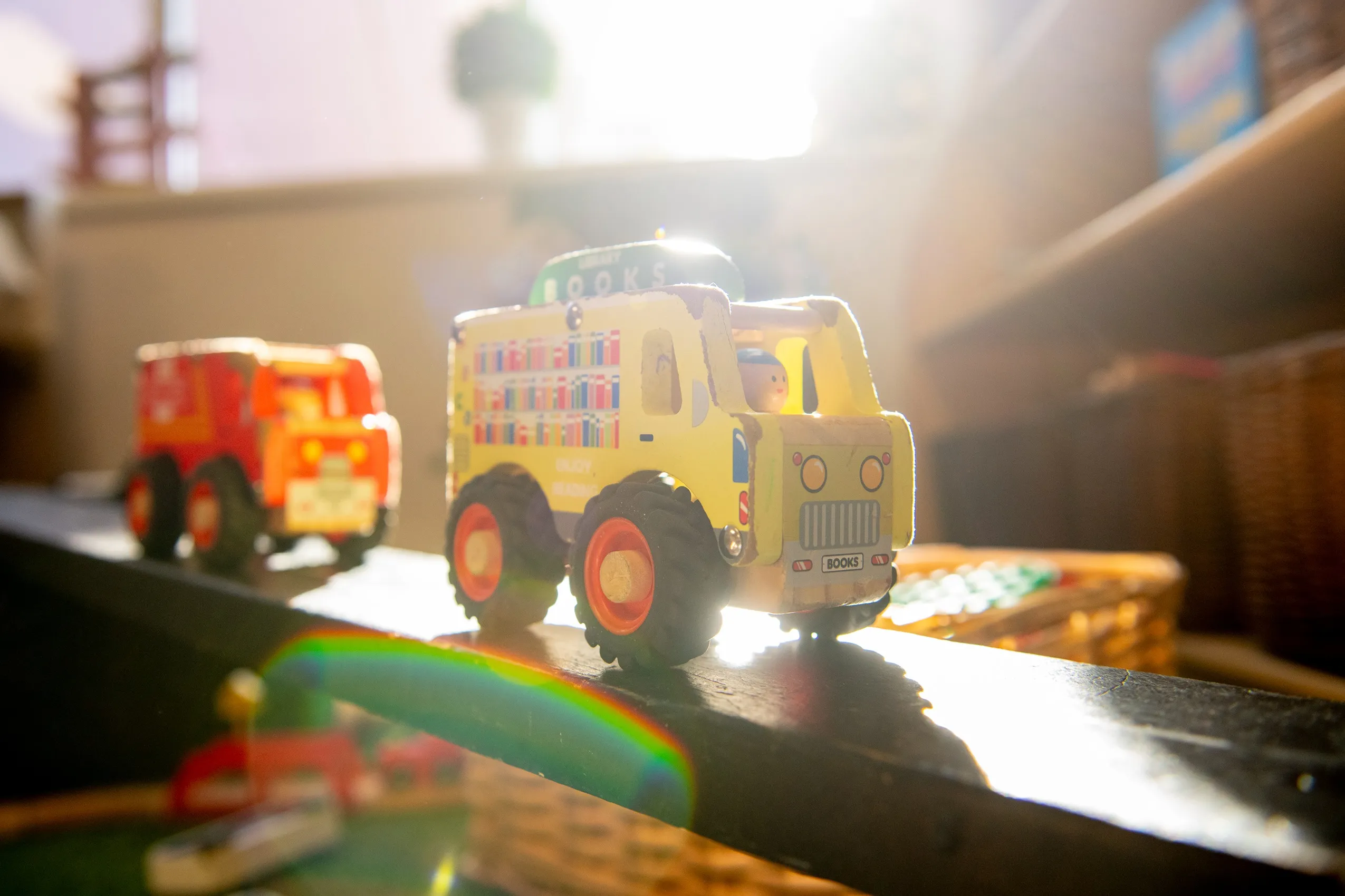 A yellow toy truck designed as a mobile library with colorful book illustrations on its sides and a 'BOOKS' license plate.