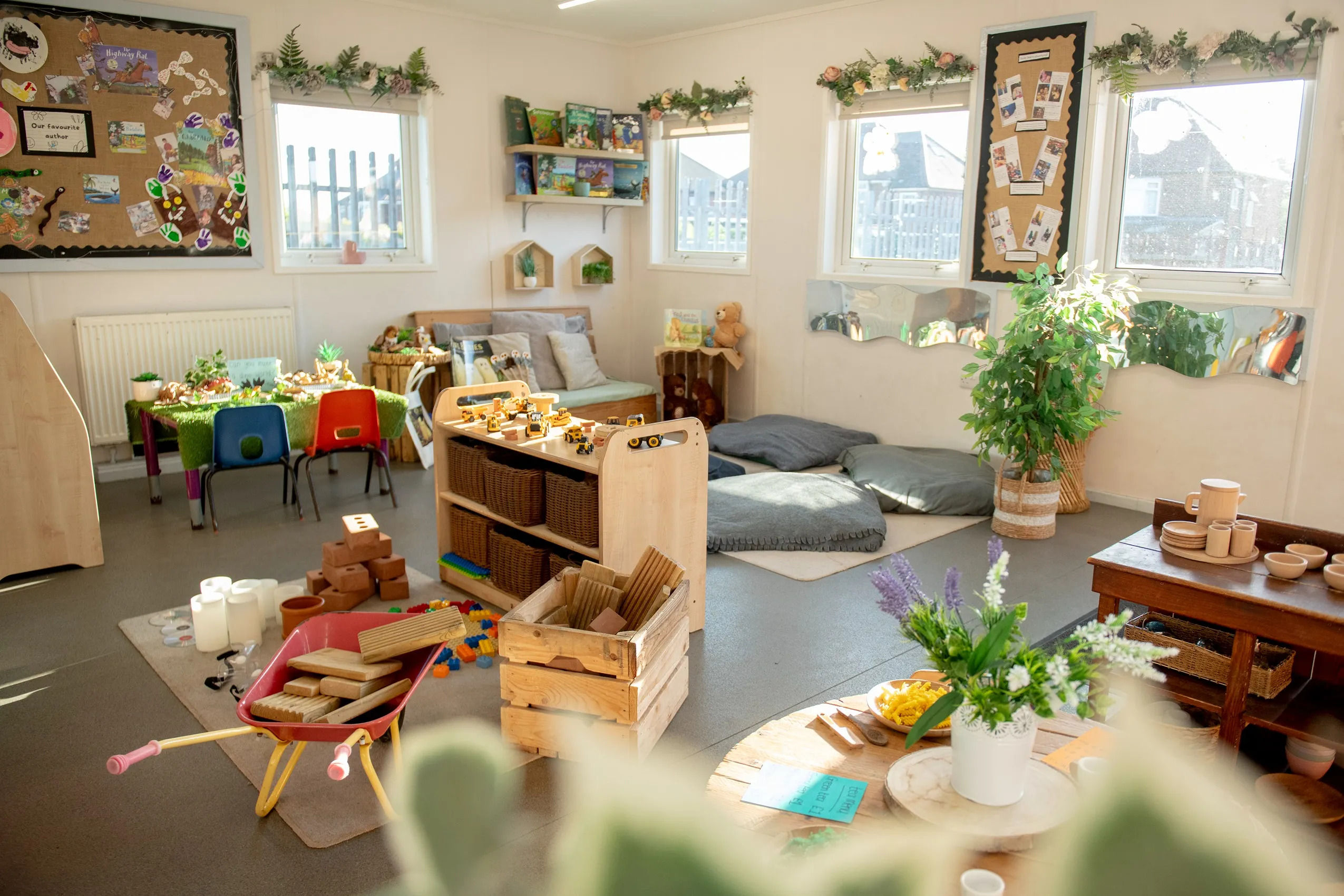 A brightly lit children's playroom with various play areas, colorful artwork, and plants.