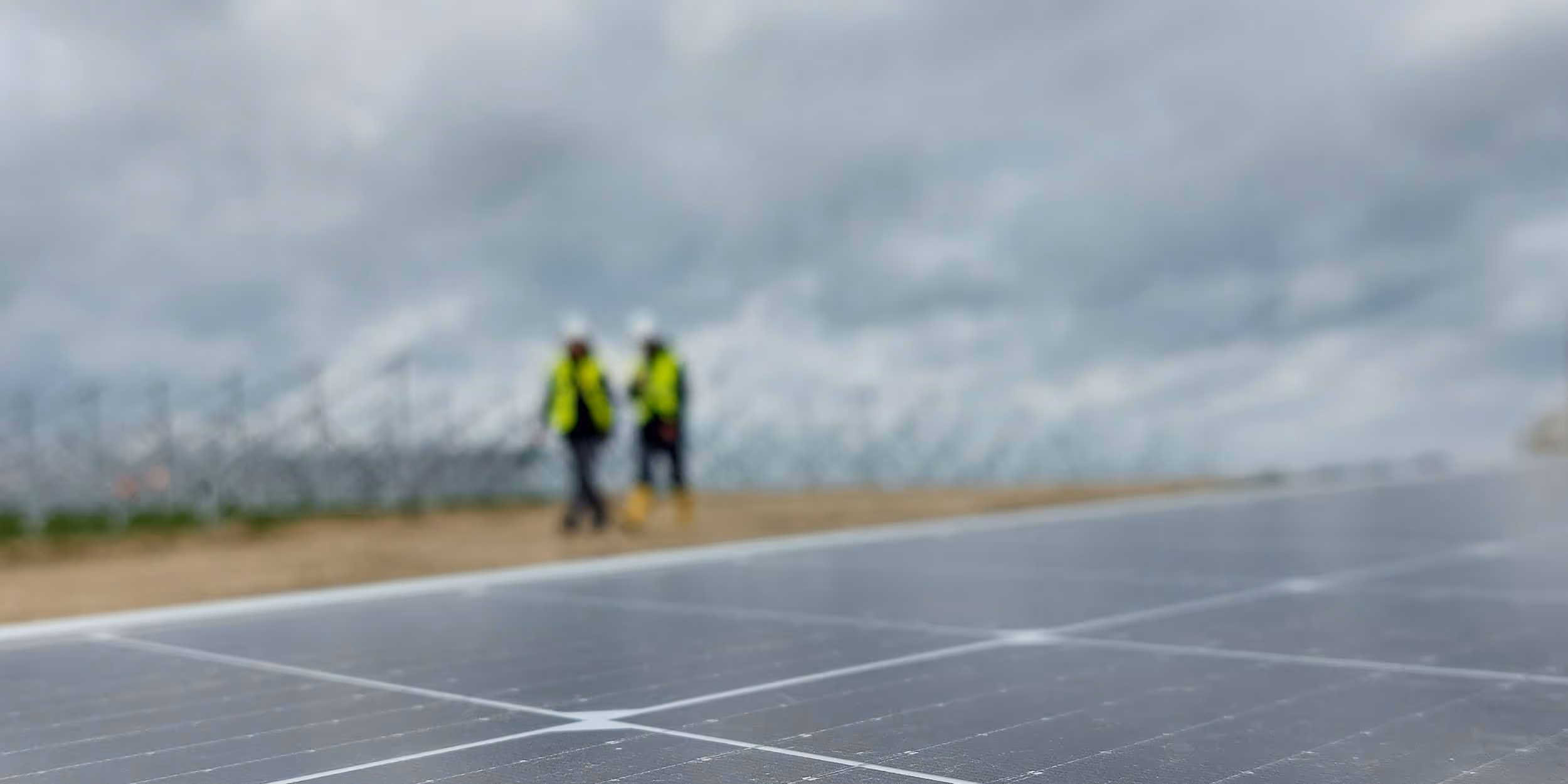 8.2 employees in background inspecting PV site with modules in front