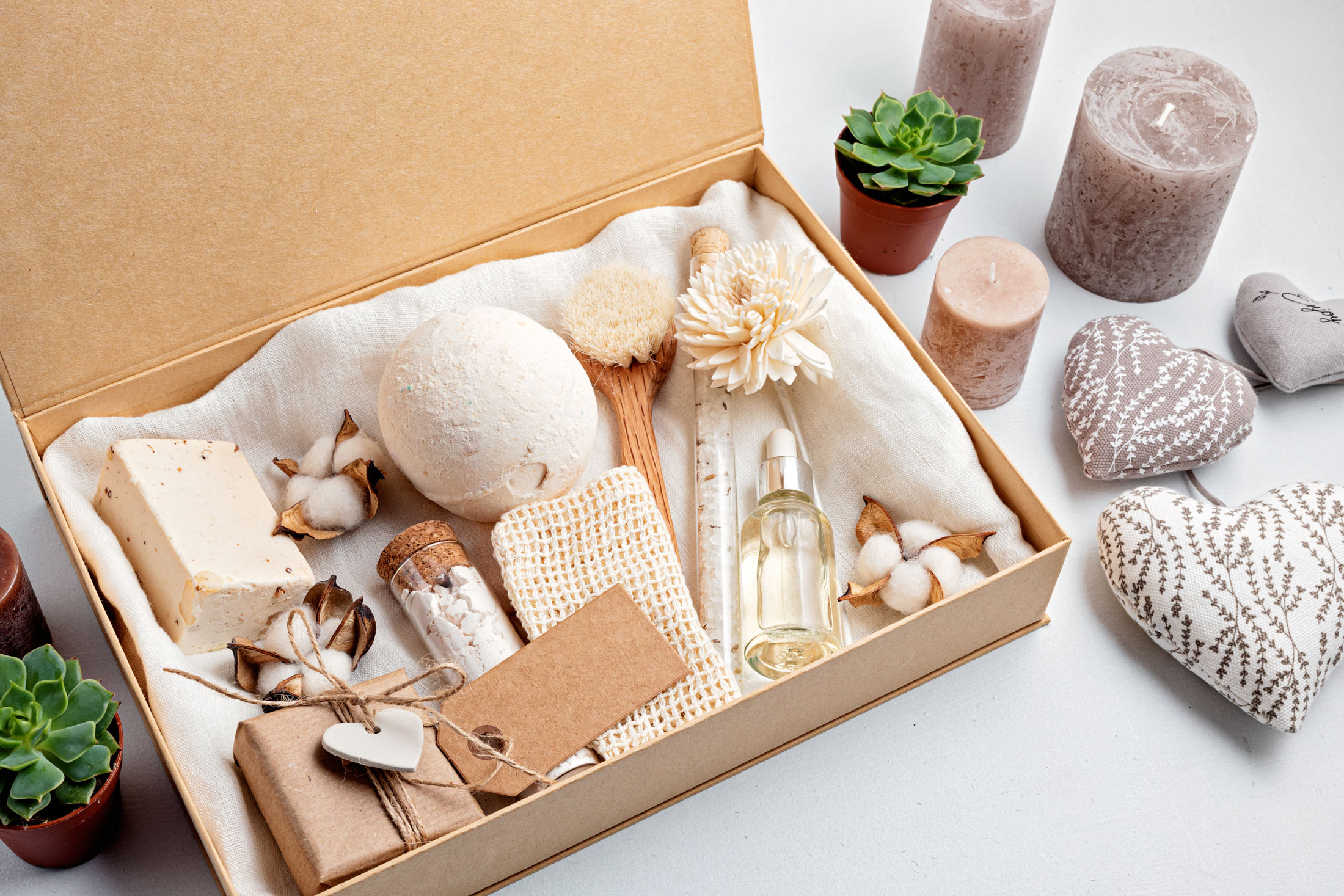 A spa gift set in a box, including soaps, candles, a brush, and a small oil bottle.
