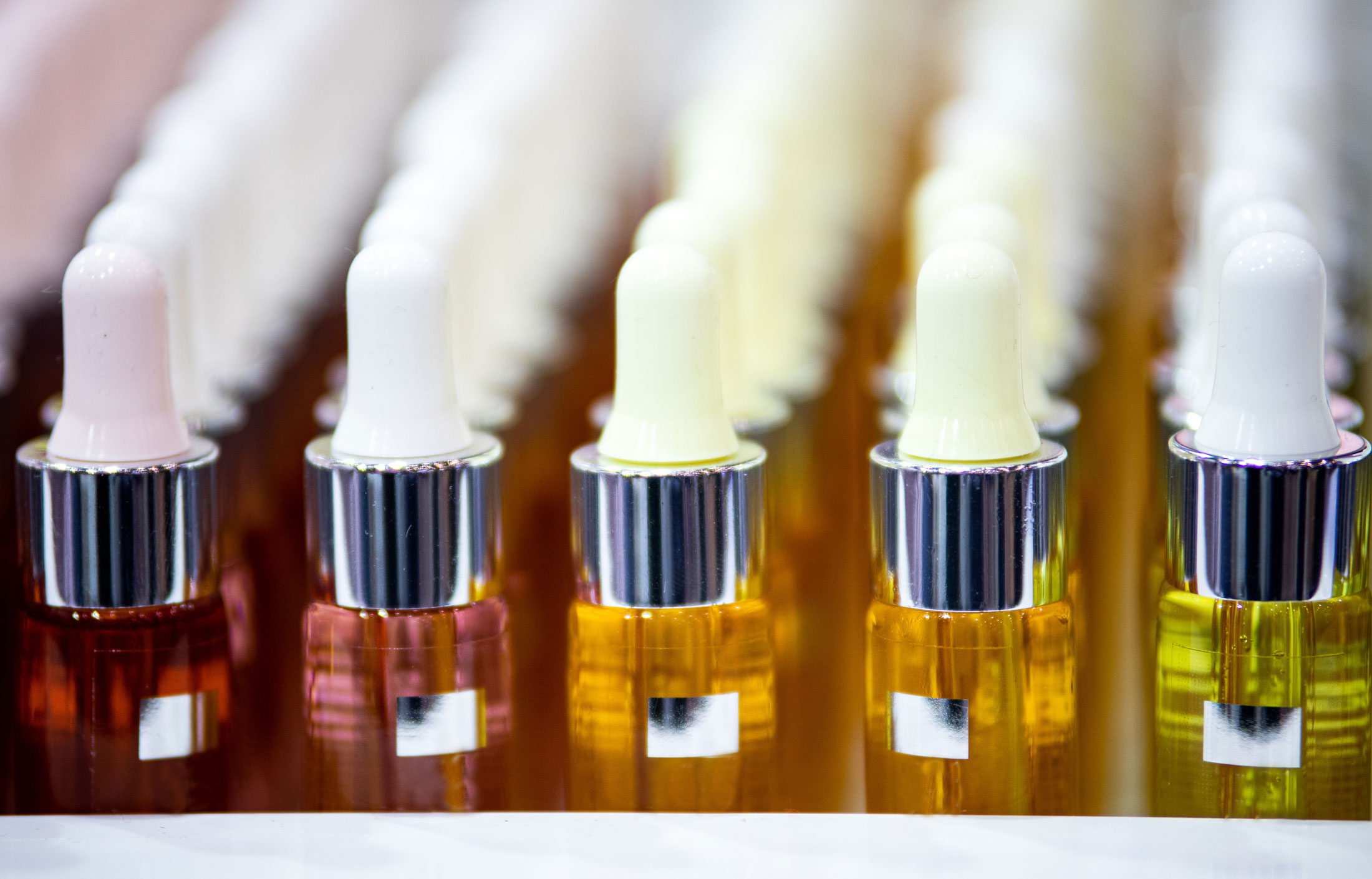 Rows of dropper bottles filled with colorful liquids lined up closely together.