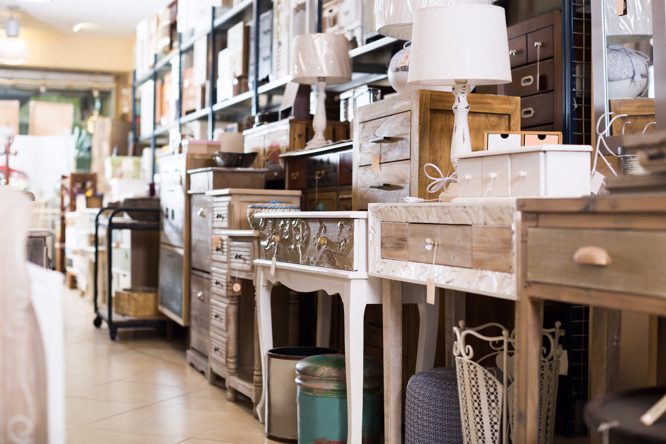 Various wooden furniture and lamps displayed in a store aisle.