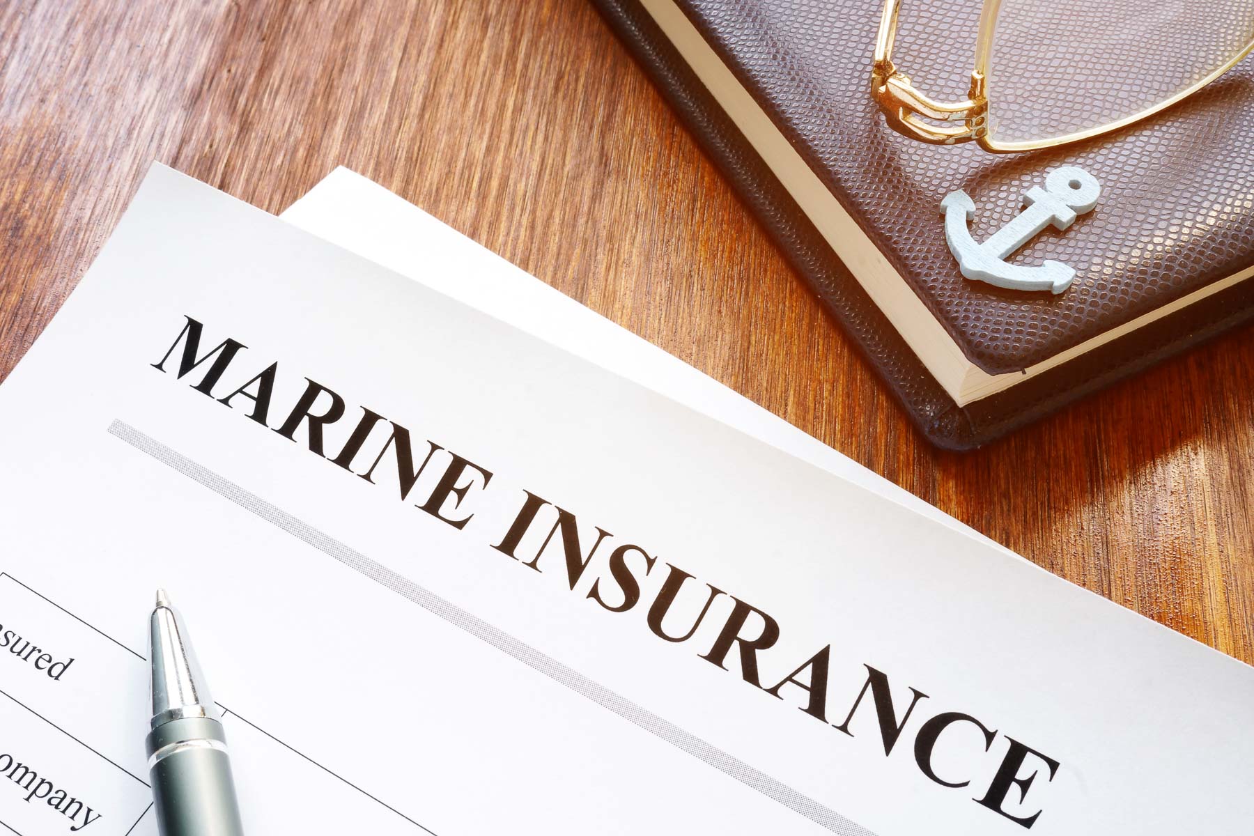 A document titled "Marine Insurance" lies on a table beside a pen and journal.